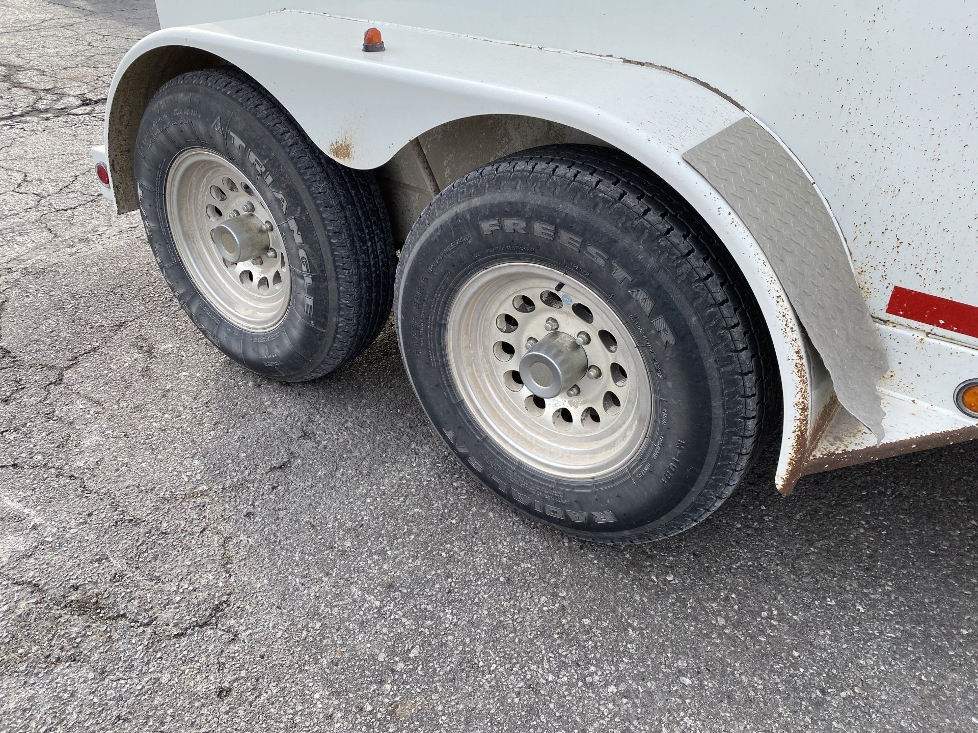 Two white trailer wheels on asphalt.