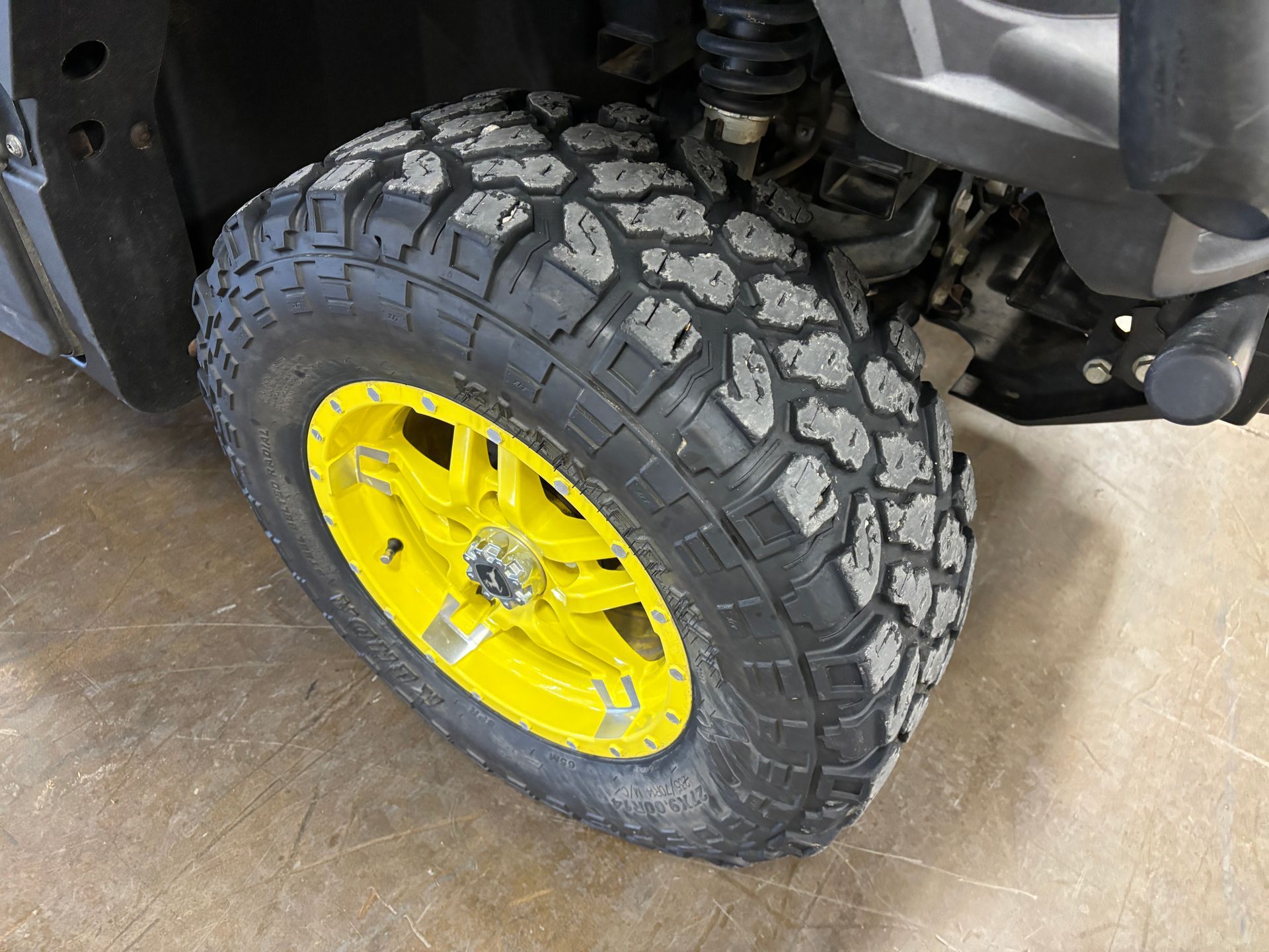 Black off-road tire on a yellow wheel, attached to a gray vehicle.