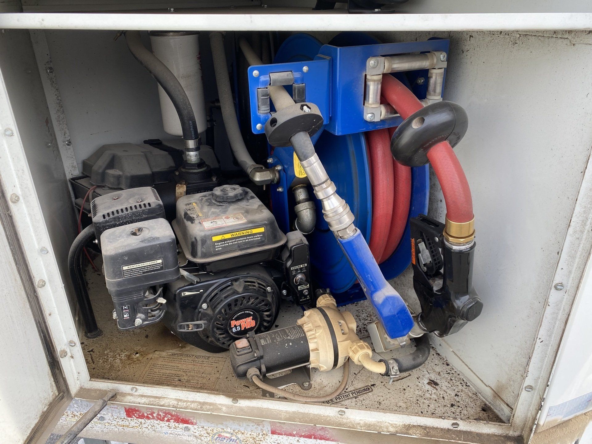 Gasoline pump inside a compartment, featuring a small engine, hoses, and nozzles.