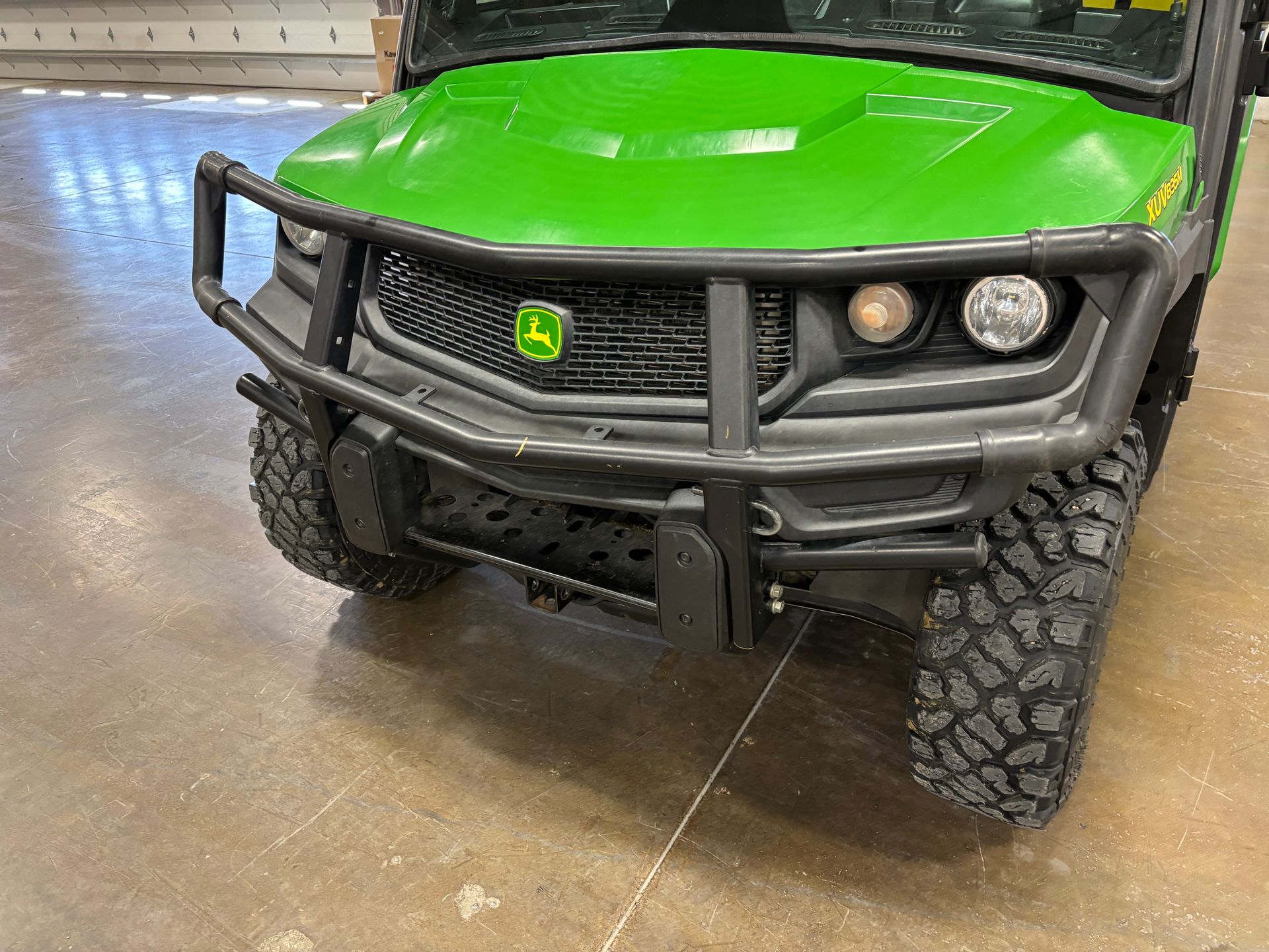 Green John Deere Gator utility vehicle with black brush guard and large tires.