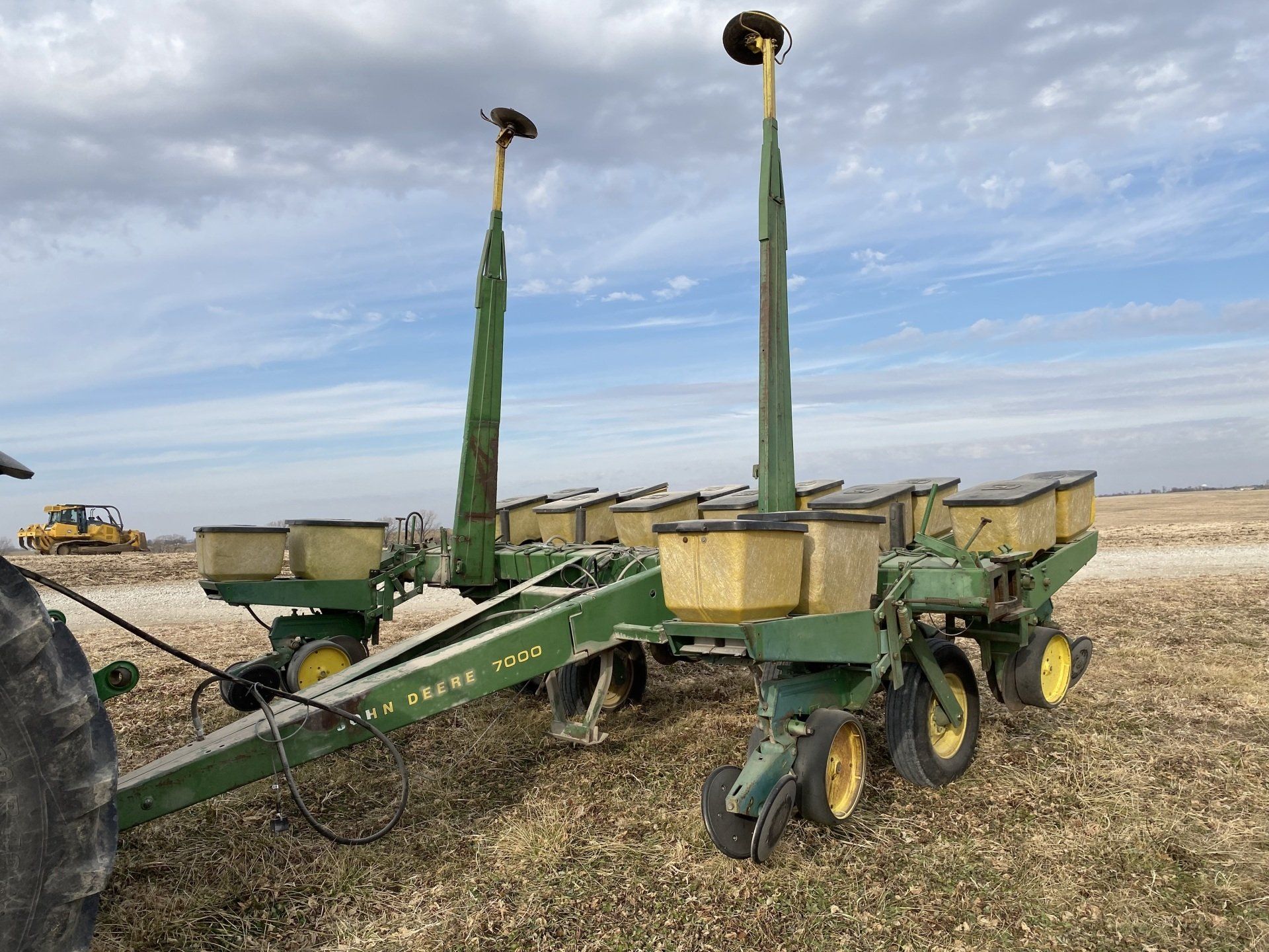 Green John Deere planter in a field on a cloudy day.