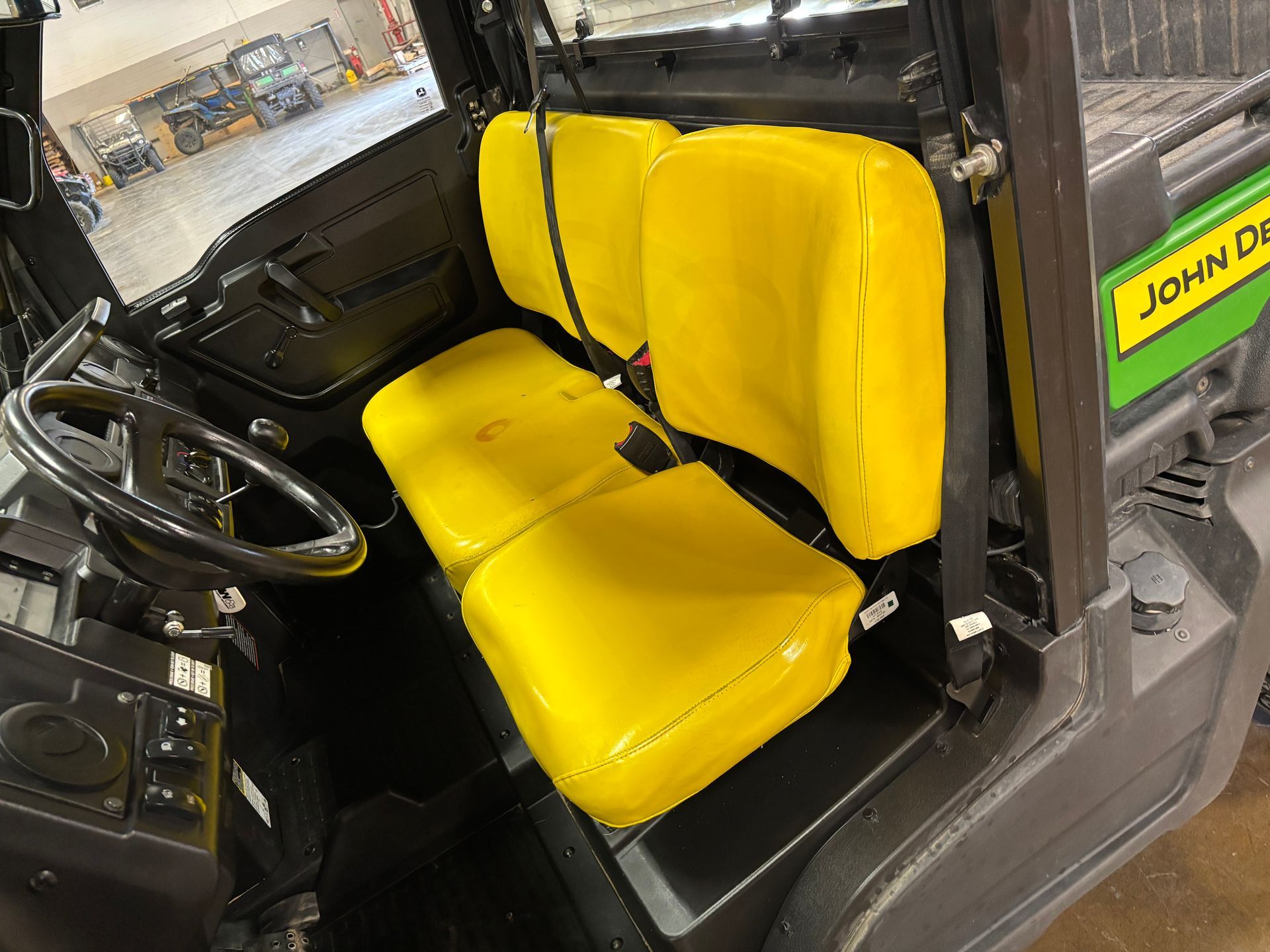 Interior view of a John Deere utility vehicle with yellow seats and a black steering wheel.