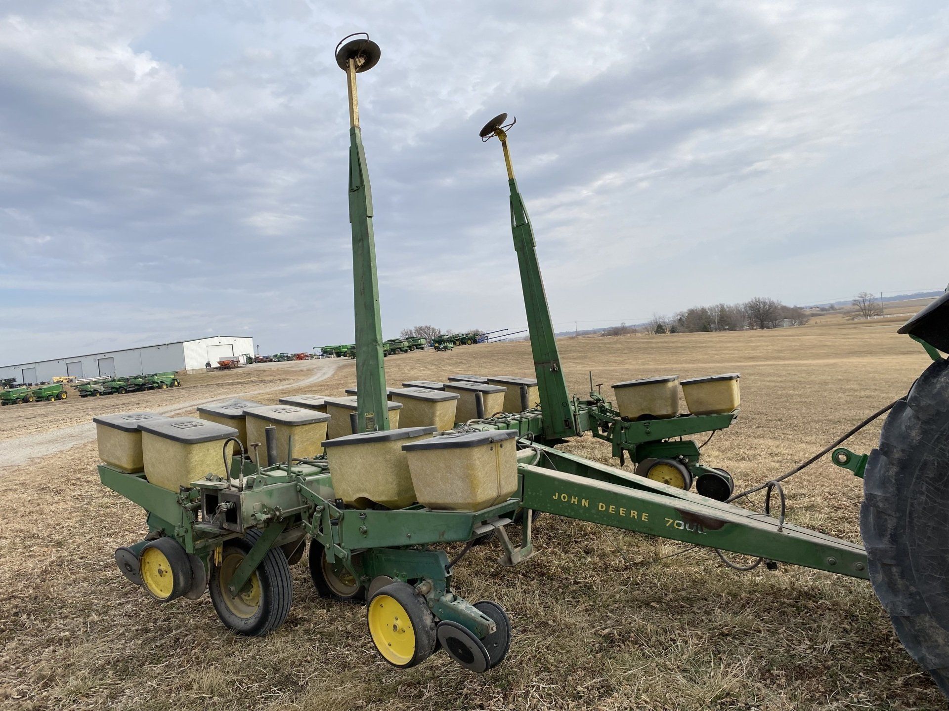 Green John Deere planter with yellow wheels in a field.