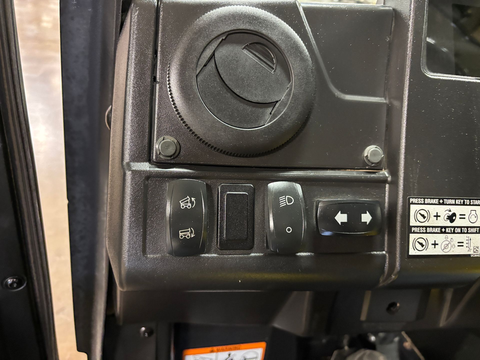 Dashboard with air vent and four black switches in a vehicle.