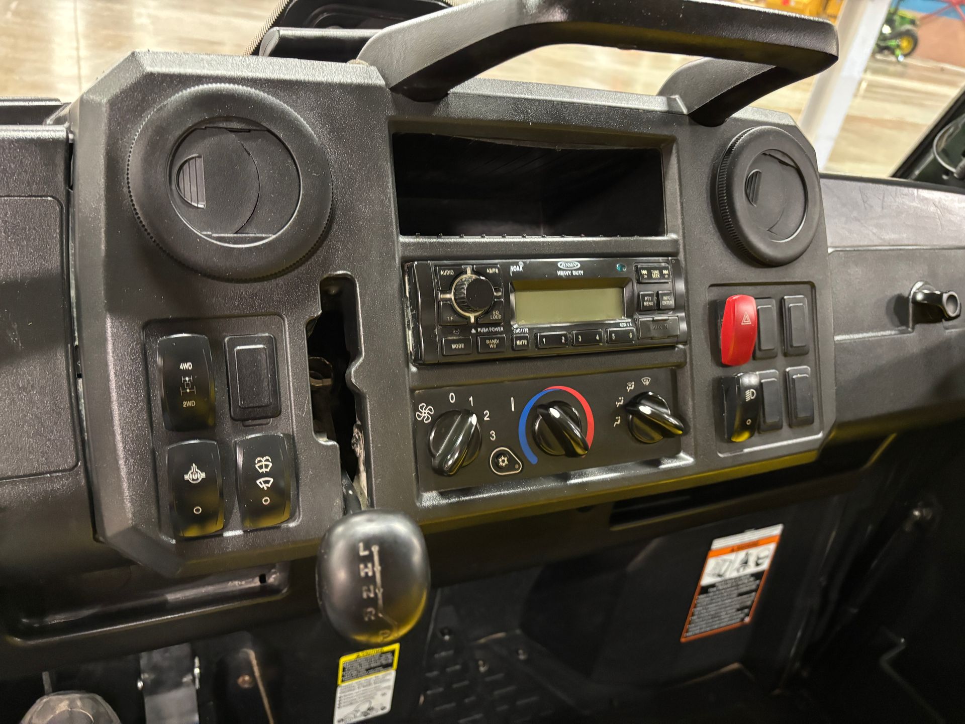 Dashboard of a utility vehicle with radio, vents, switches, and gear shift. Black interior.