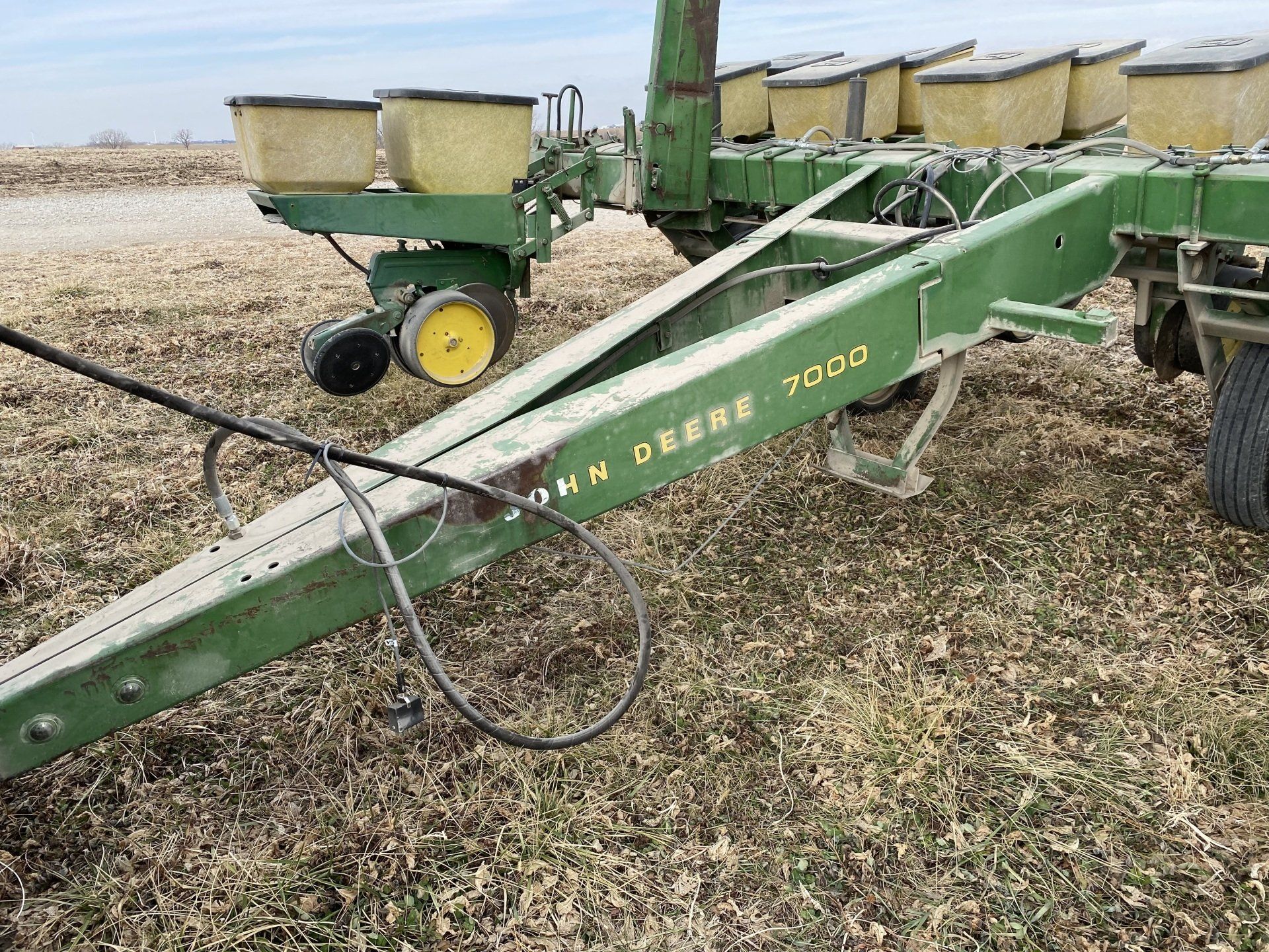Green John Deere 7000 planter in a field, with yellow seed hoppers.