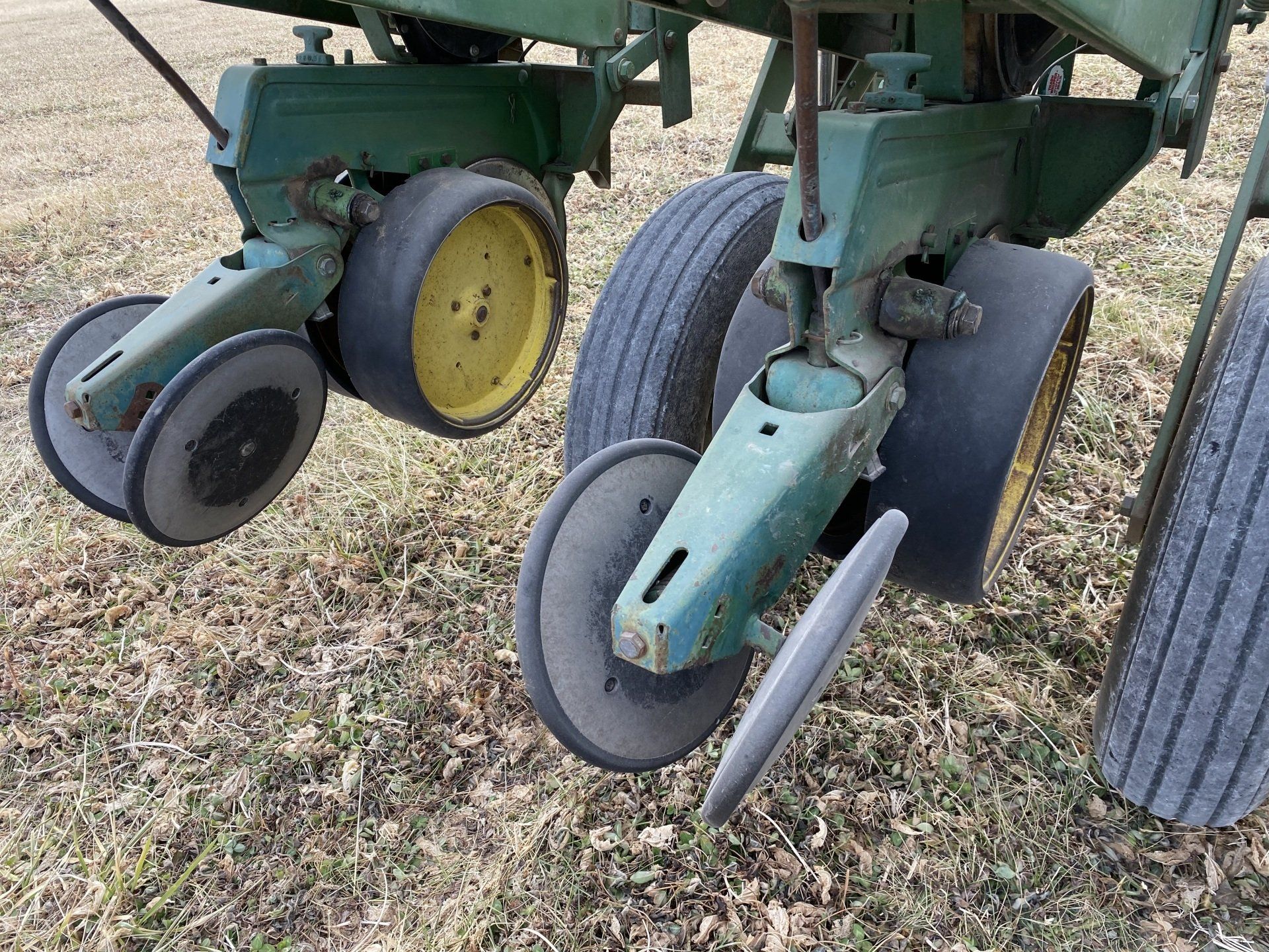 Green and yellow agricultural planter machinery on a field of dry grass.