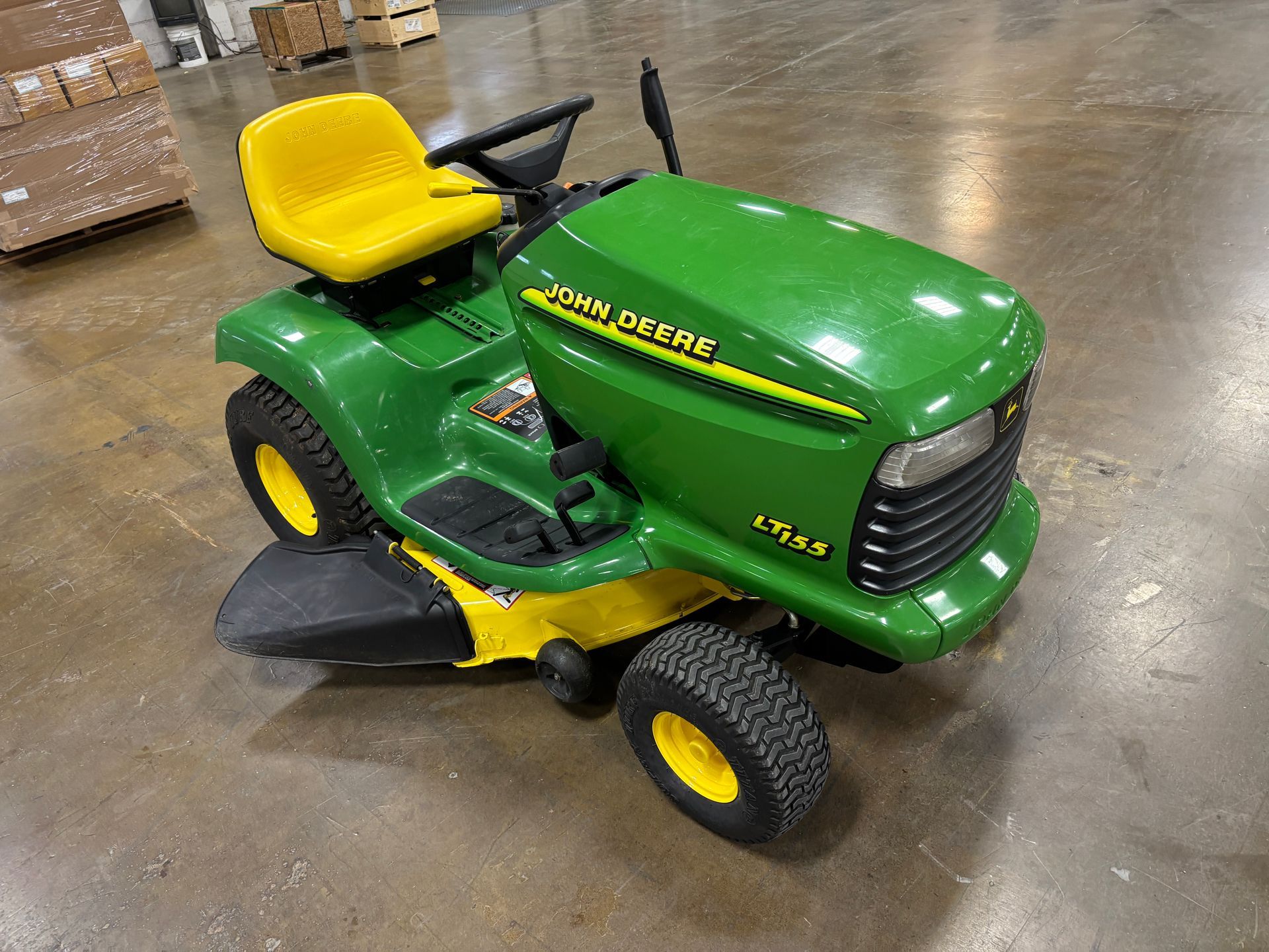 Green and yellow John Deere L105 riding lawnmower on a gray surface.