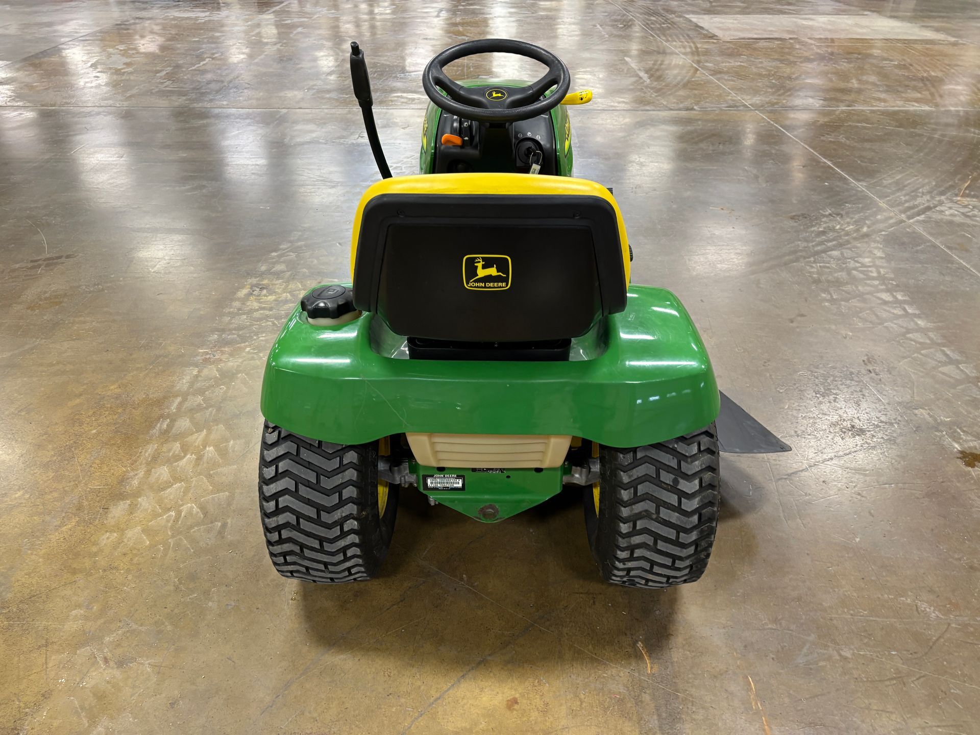 Green and yellow John Deere riding lawn mower, rear view.