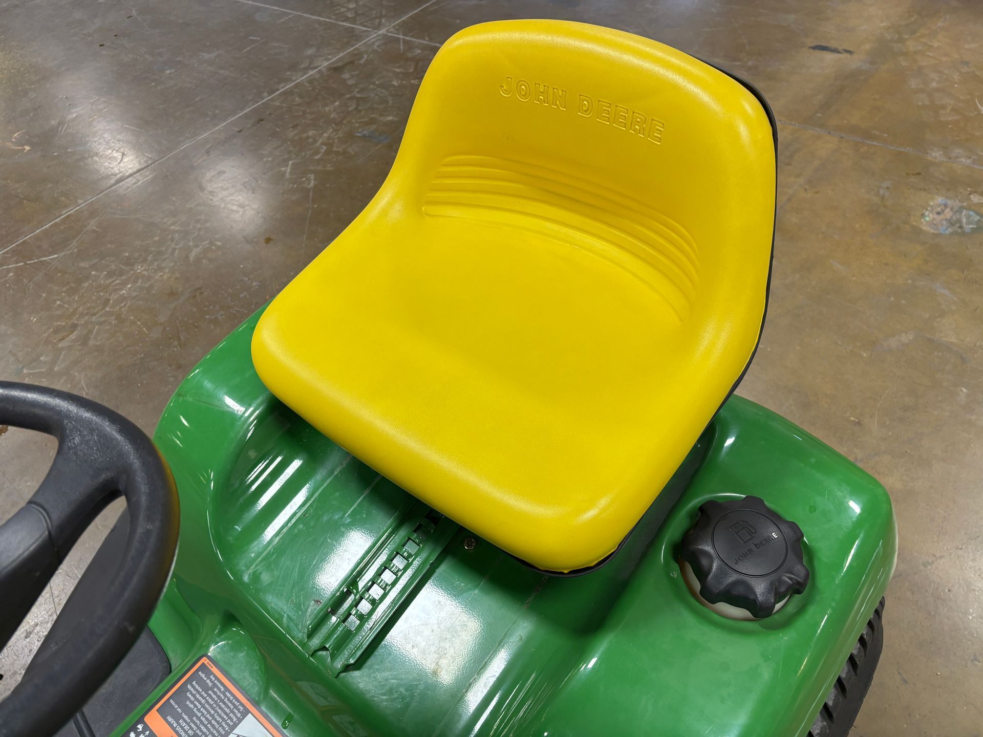 Yellow seat on a green lawnmower. John Deere logo is visible.
