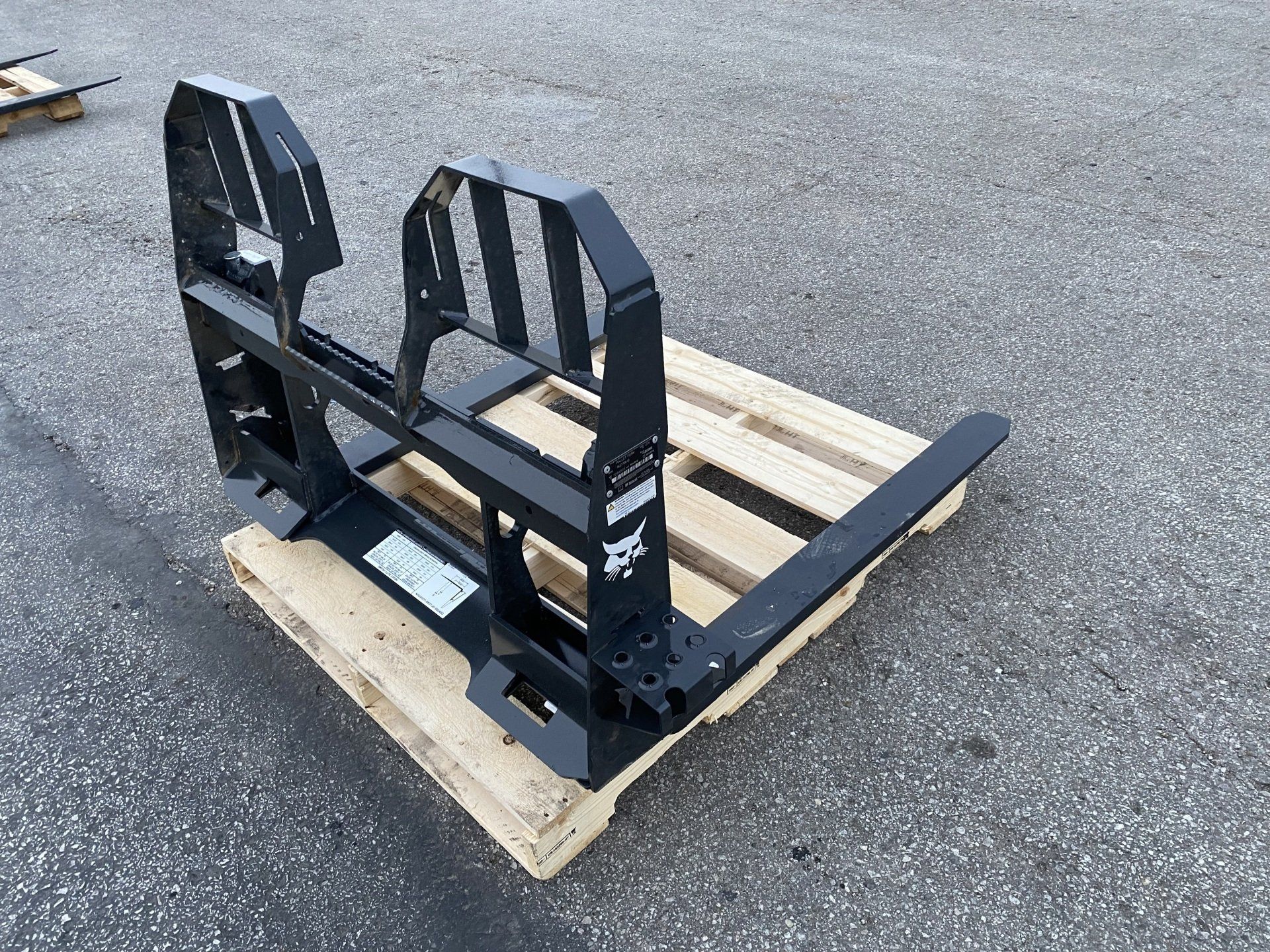 Black Bobcat pallet fork attachment on a wooden pallet.