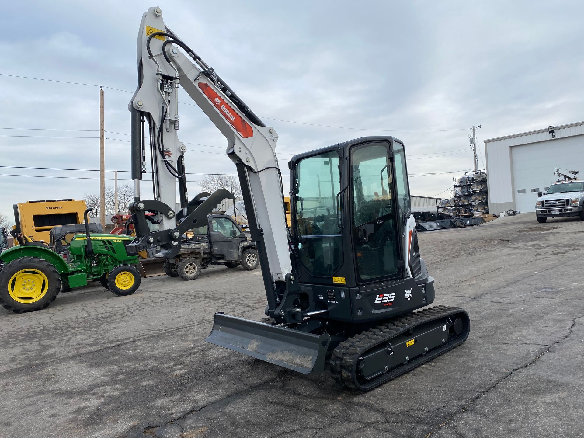 Bobcat mini excavator with a forestry cutter attachment. Outdoor setting.