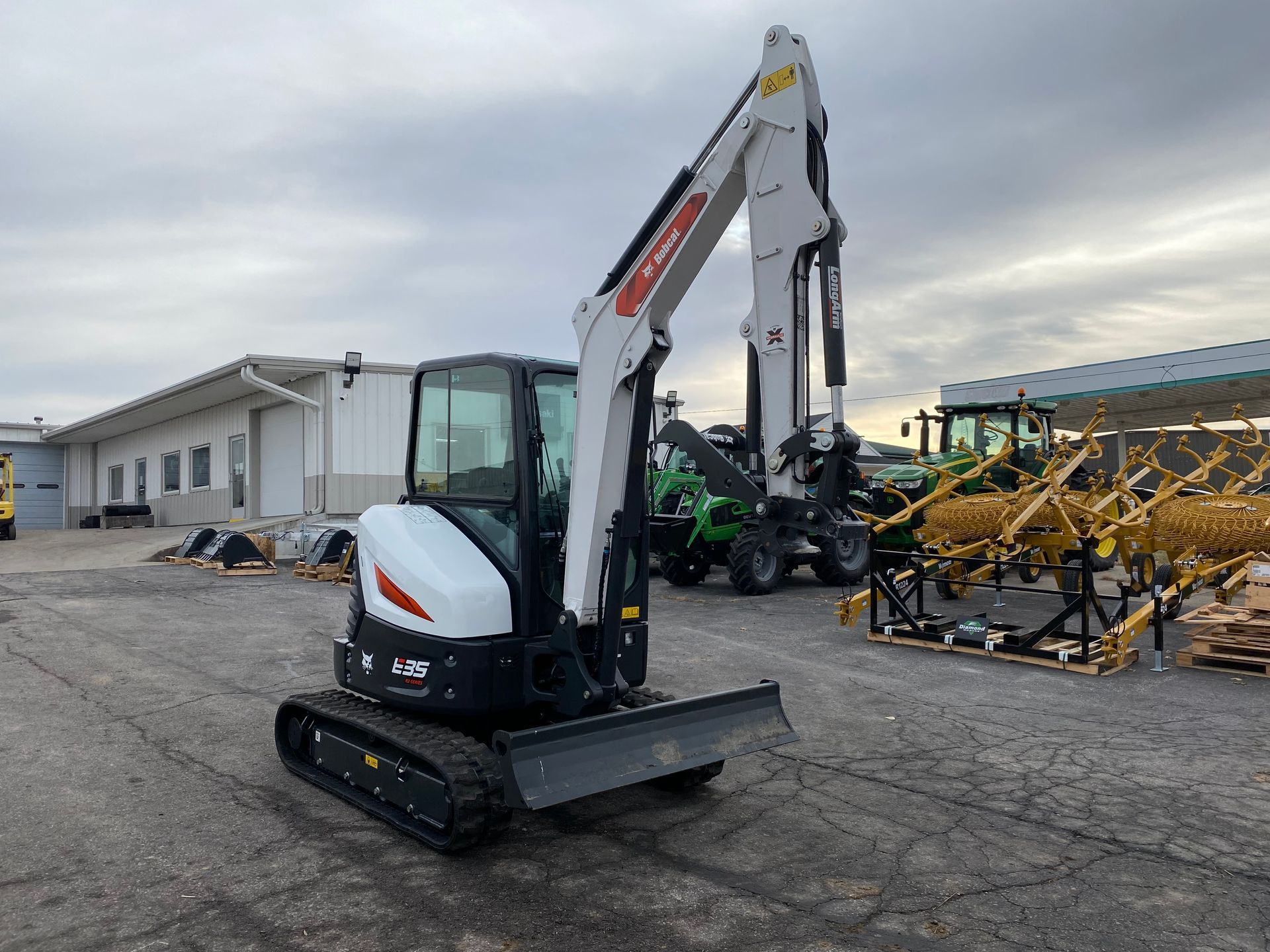 A white Bobcat E35 mini excavator sits on asphalt in front of a building.
