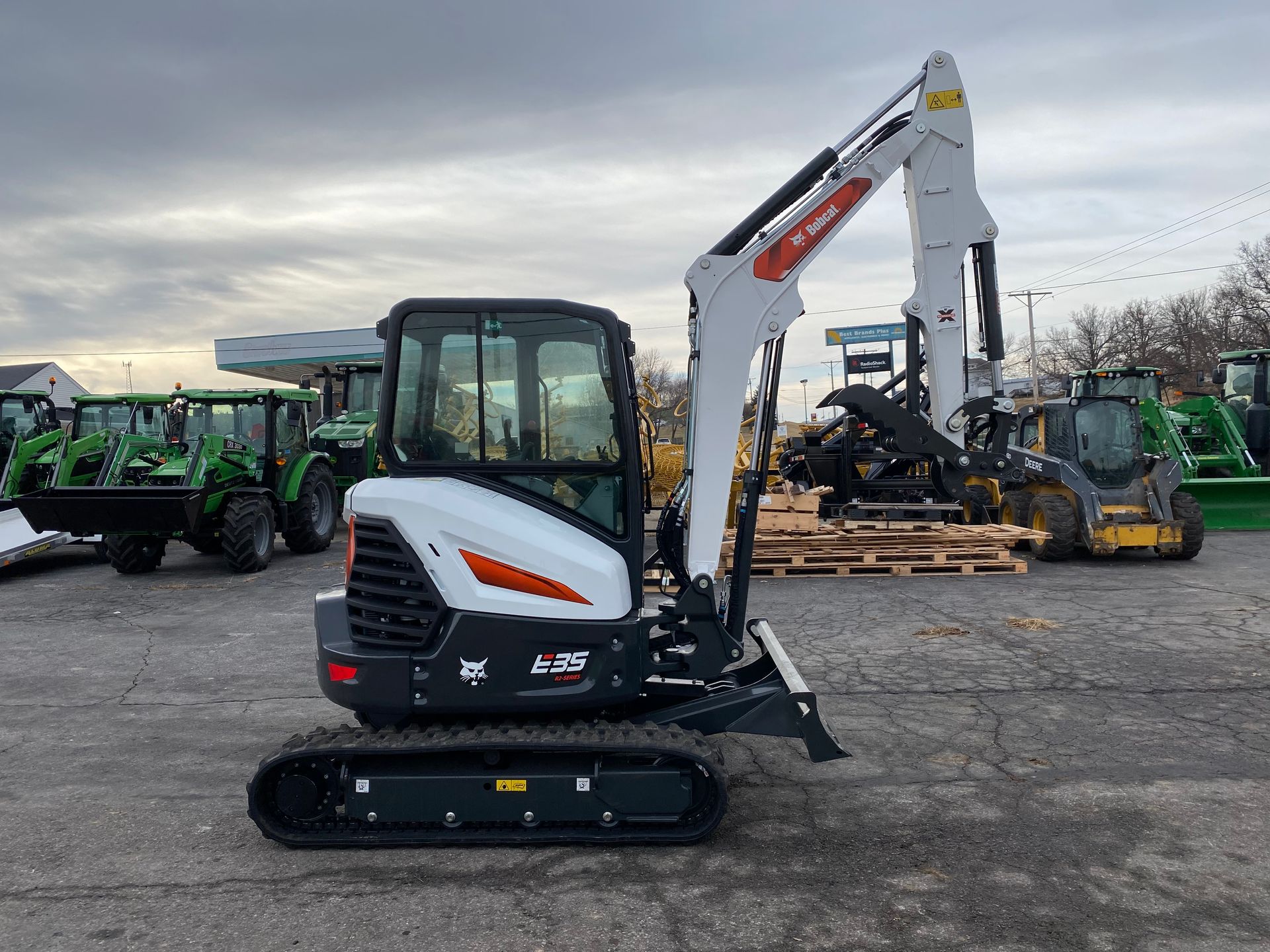 White and orange Bobcat mini excavator with black tracks on a paved surface.
