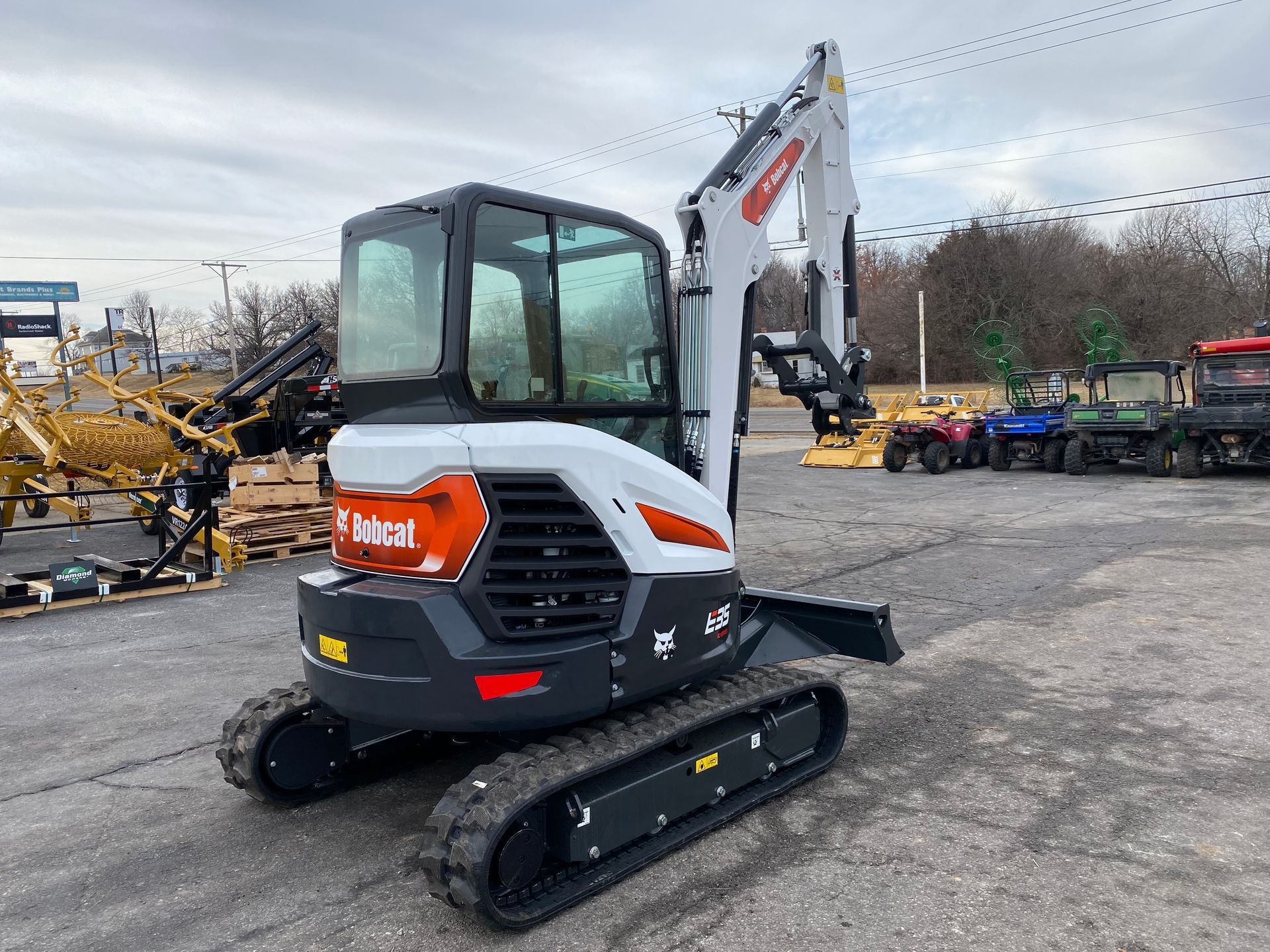 Bobcat E20 excavator on tracks, white and gray with orange logo, parked outdoors on asphalt.