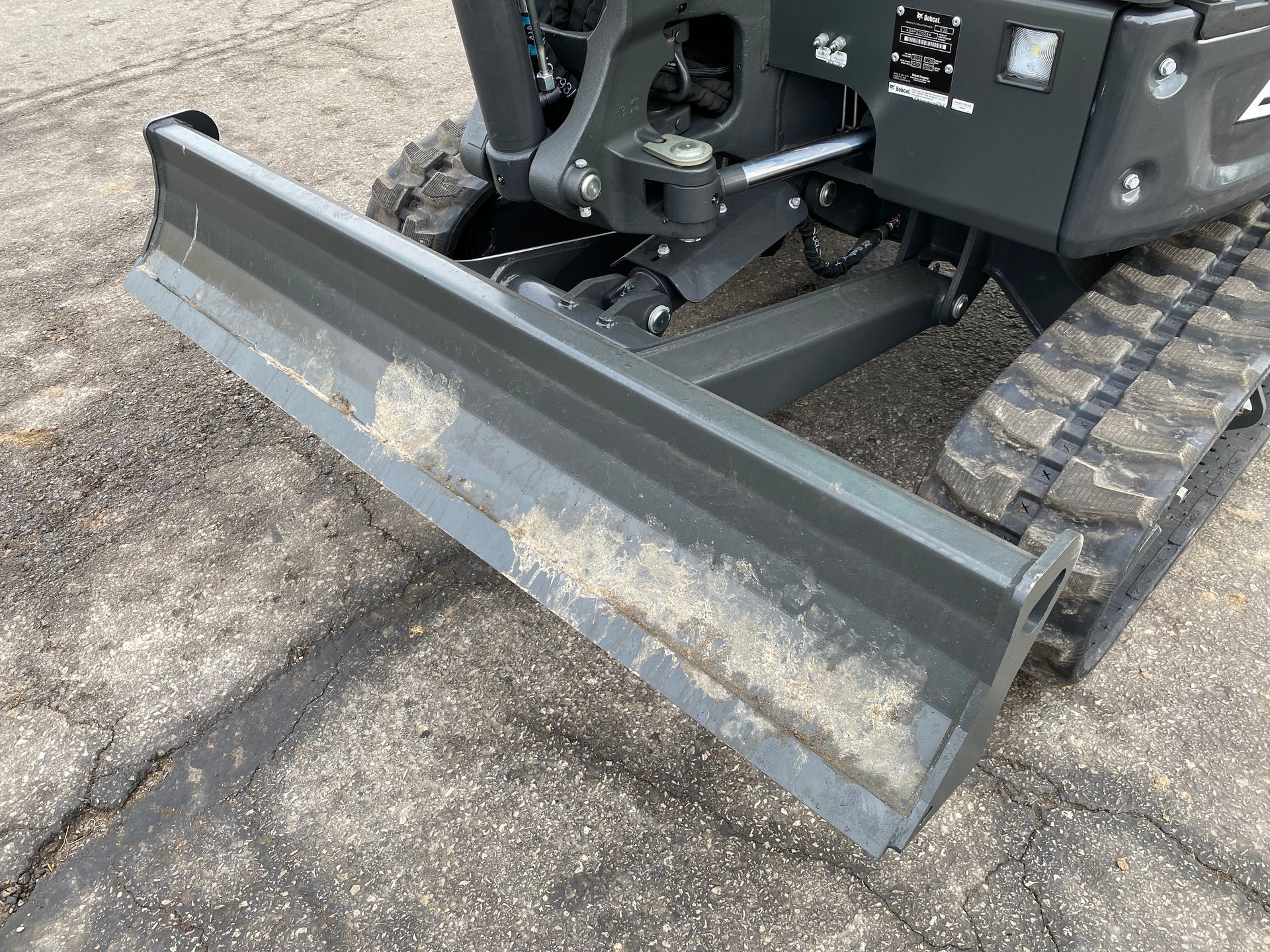 Close-up of a dark gray mini excavator blade, likely for leveling ground.