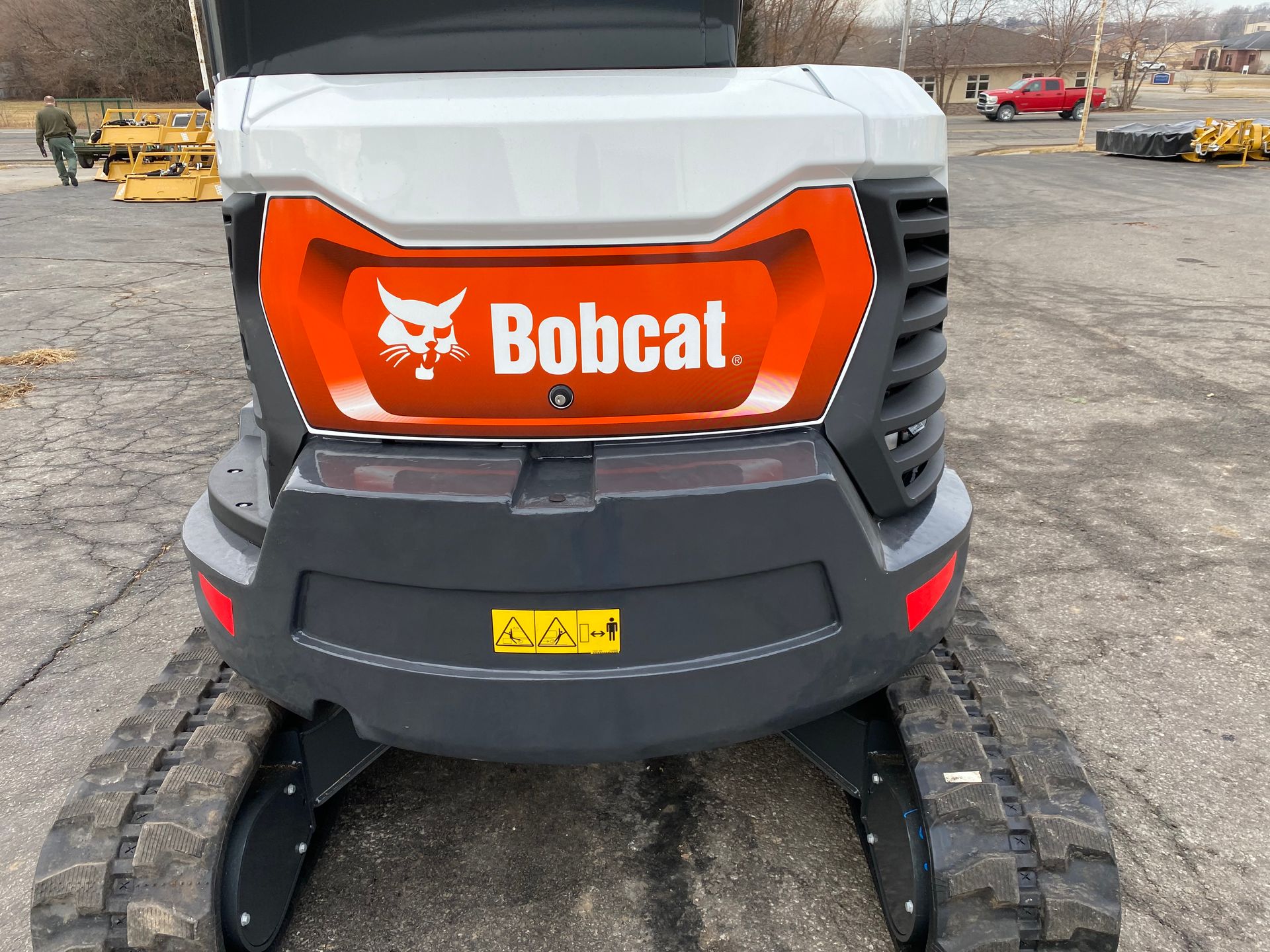Bobcat mini excavator: Close-up of rear, orange and gray body, black tracks, logo visible.