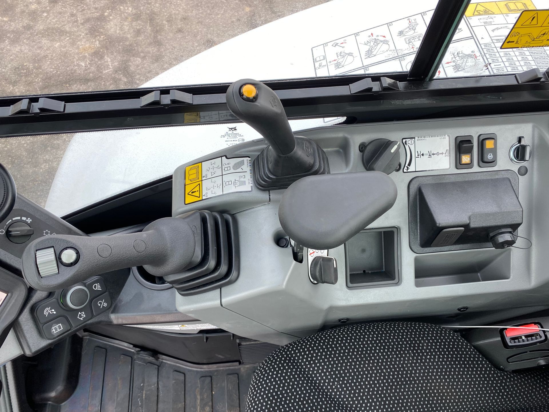 Control panel of heavy machinery with joysticks, switches, and a control lever.