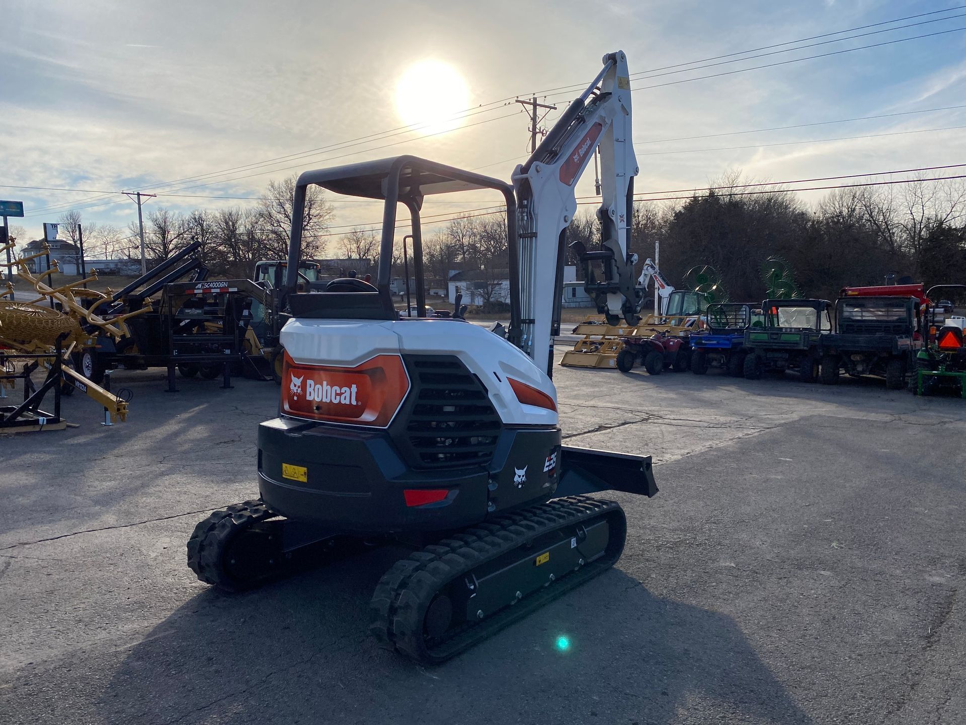 Bobcat mini excavator on display at a dealership, white and orange with tracks.