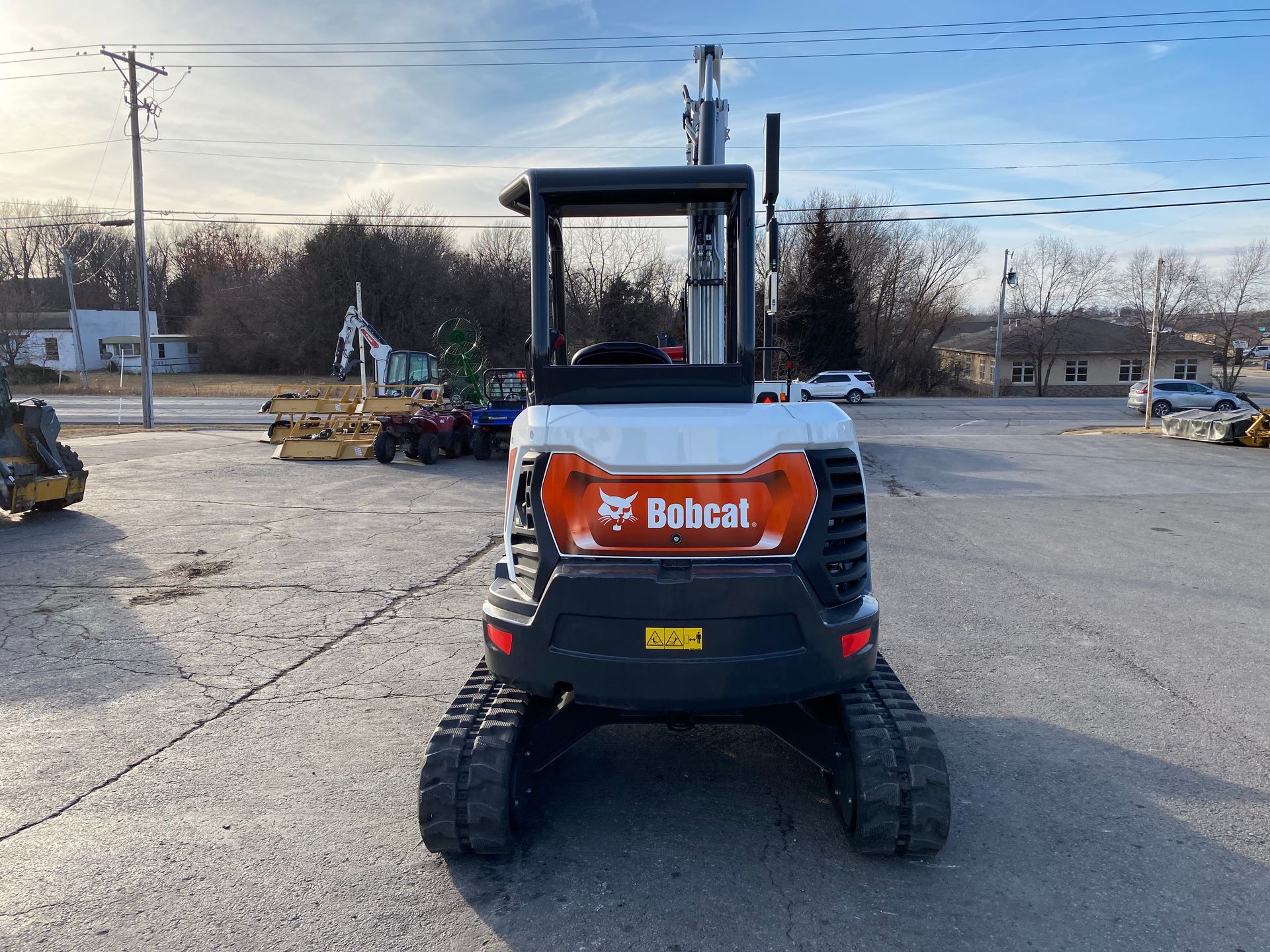 Bobcat mini excavator, front view, on tracks, parked outdoors, sunny day.
