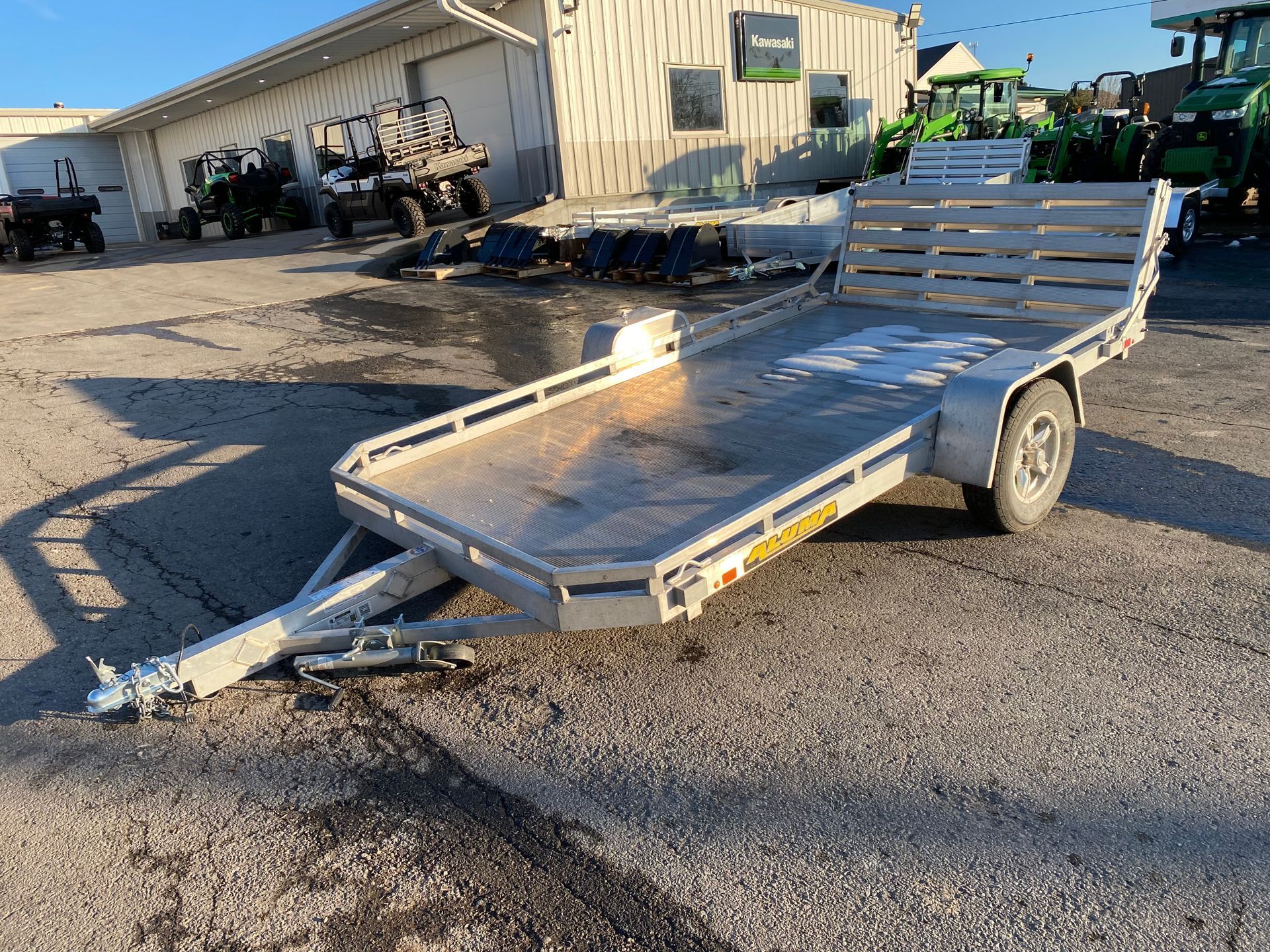 Aluminum utility trailer with slatted sides and rear, parked on asphalt.