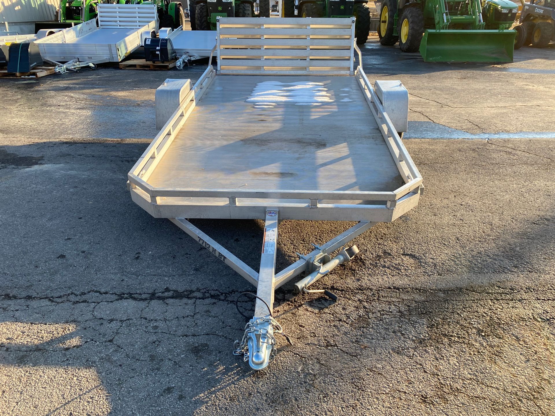 Silver utility trailer with wooden slats, parked outside.