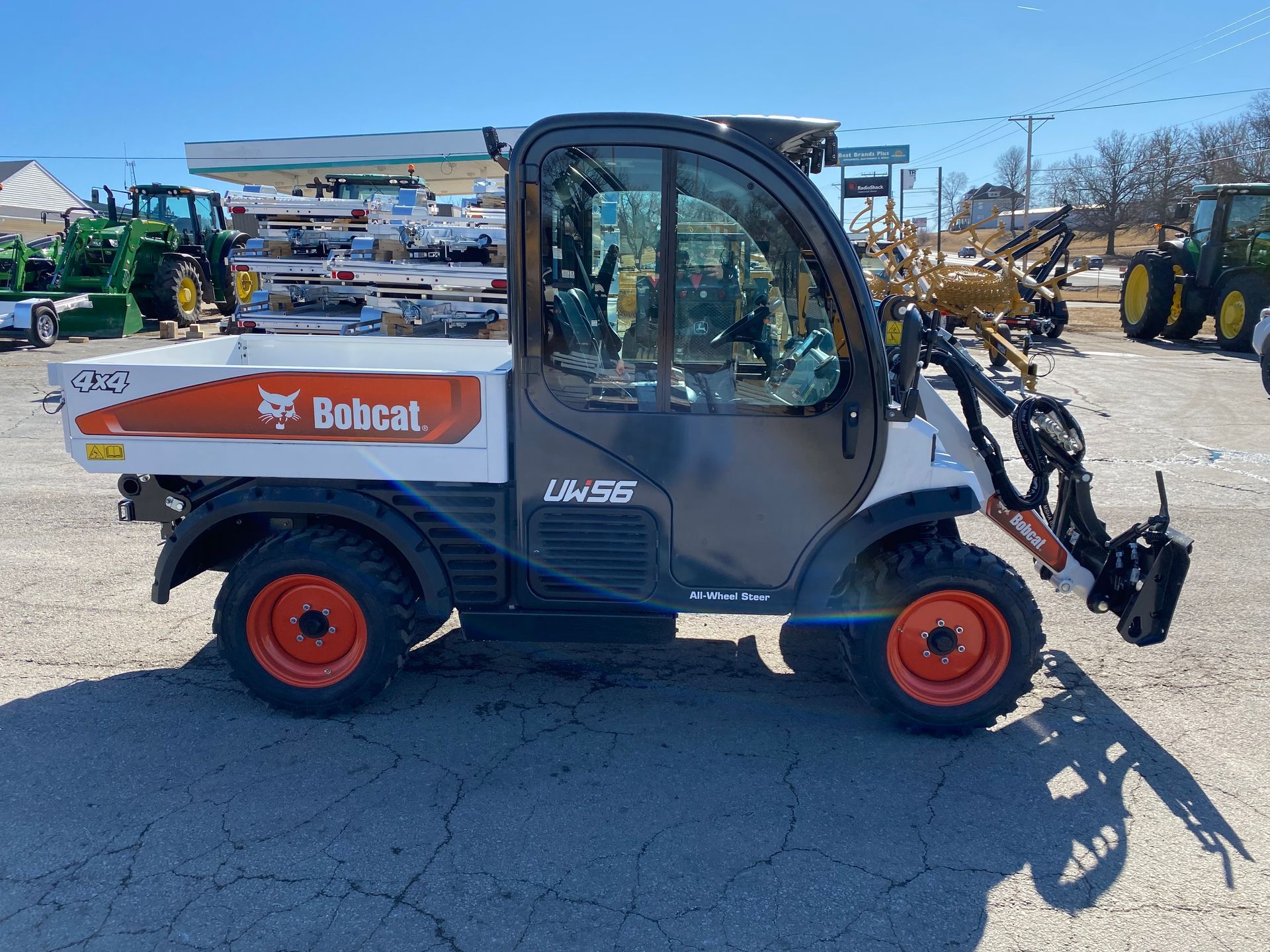 Bobcat utility vehicle, white with orange wheels, parked outside a dealership.