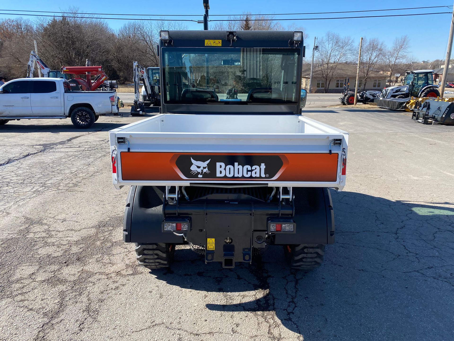 Rear view of a Bobcat utility vehicle with a white bed and black frame, parked outside.