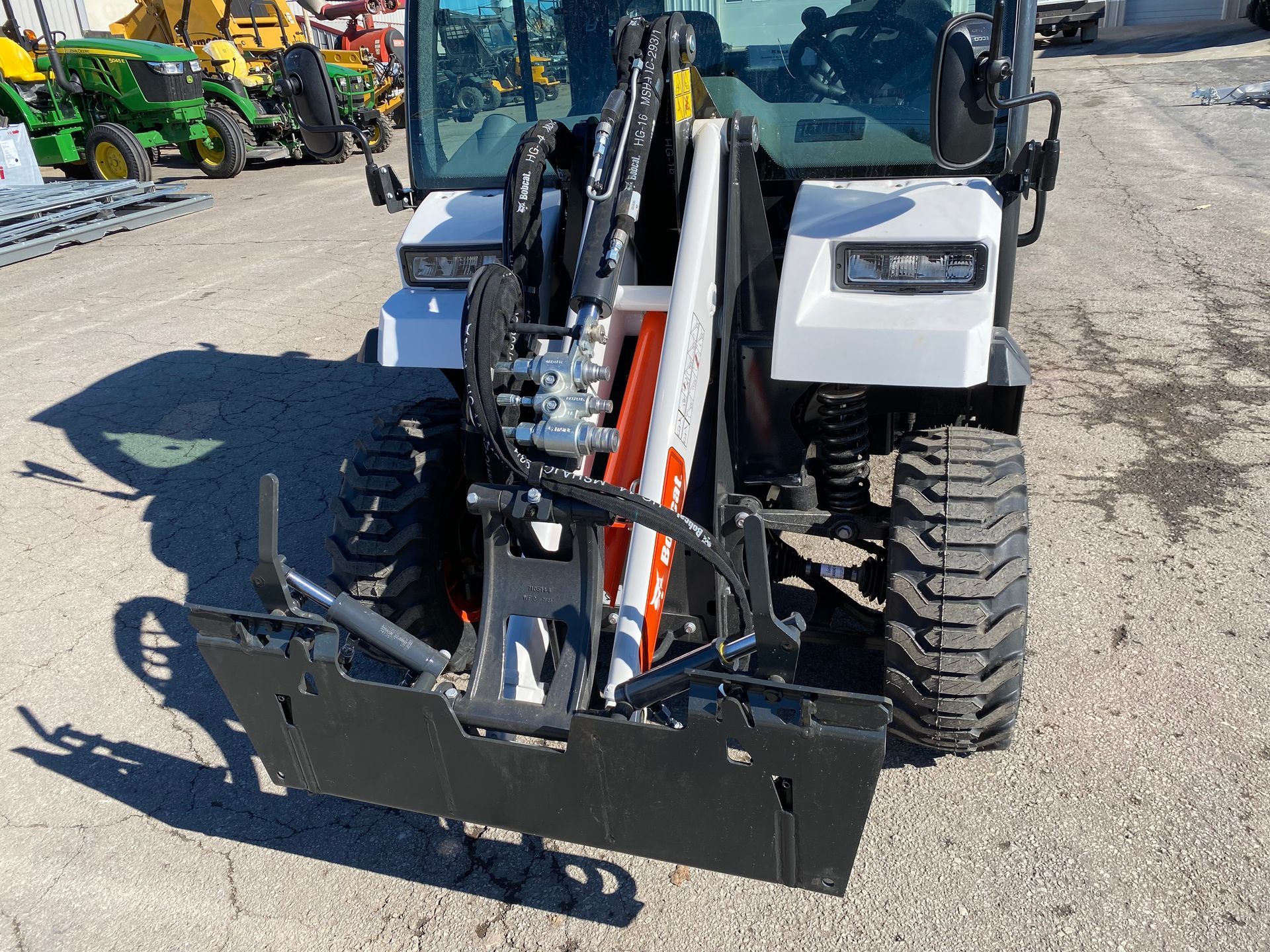 White compact tractor with black attachment; outdoors.
