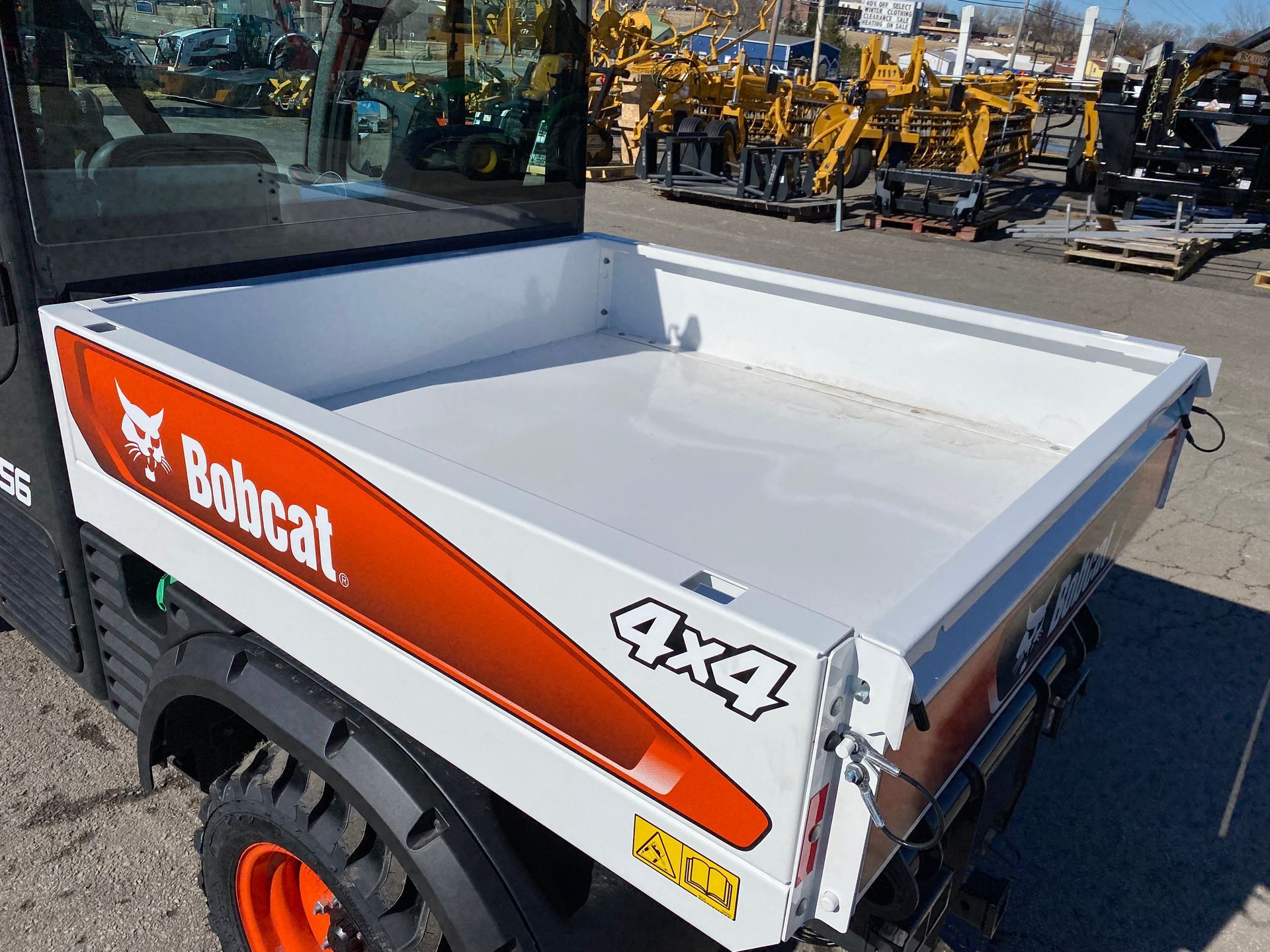 White Bobcat utility vehicle with a white cargo bed. Shows the 4x4 decal on the side.
