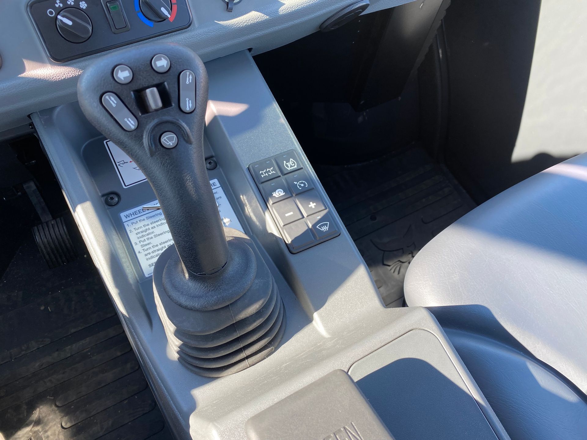 Interior of a vehicle's control panel. Joystick with buttons and additional switches are visible.