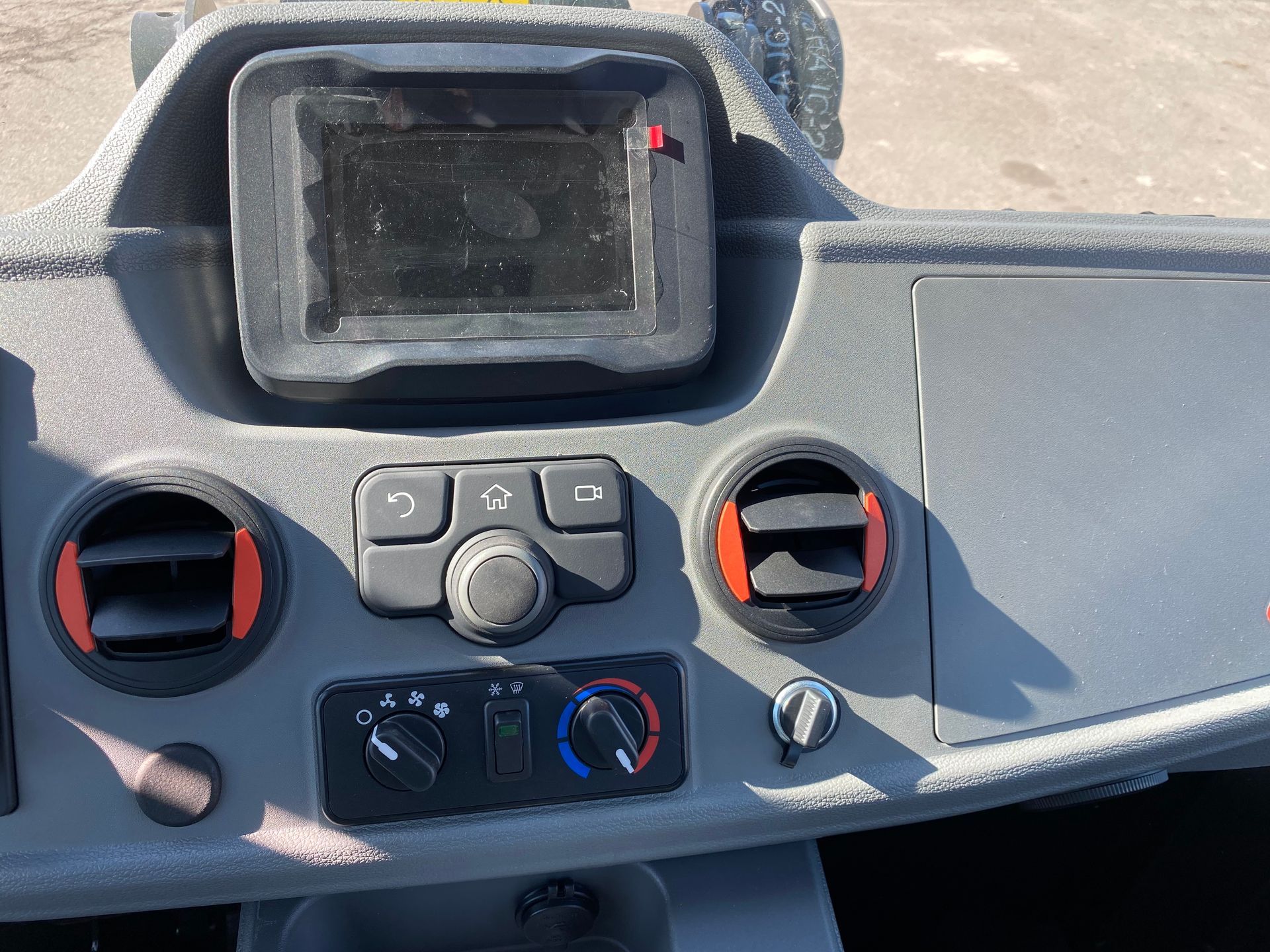 Gray dashboard of a vehicle with a screen, vents, and controls.
