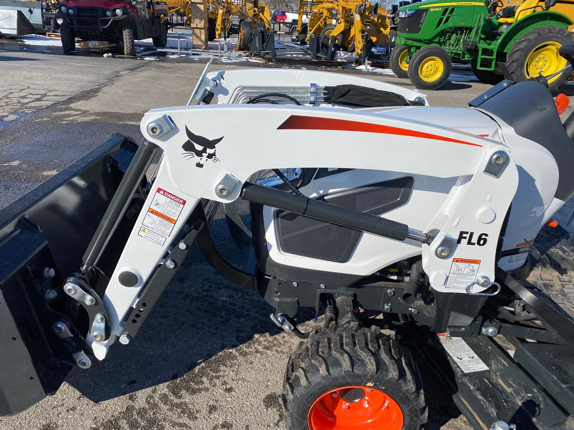 White Bobcat FL6 tractor with front loader attachment. Orange and green accents, outdoor setting.