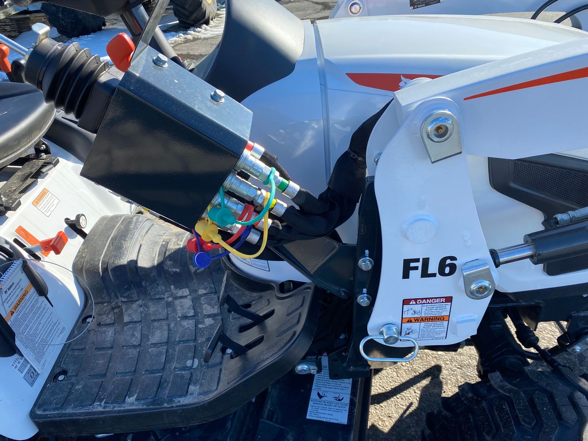 Close-up of Bobcat FL6 tractor controls, showing the joystick, hydraulic lines, and the tractor's side.