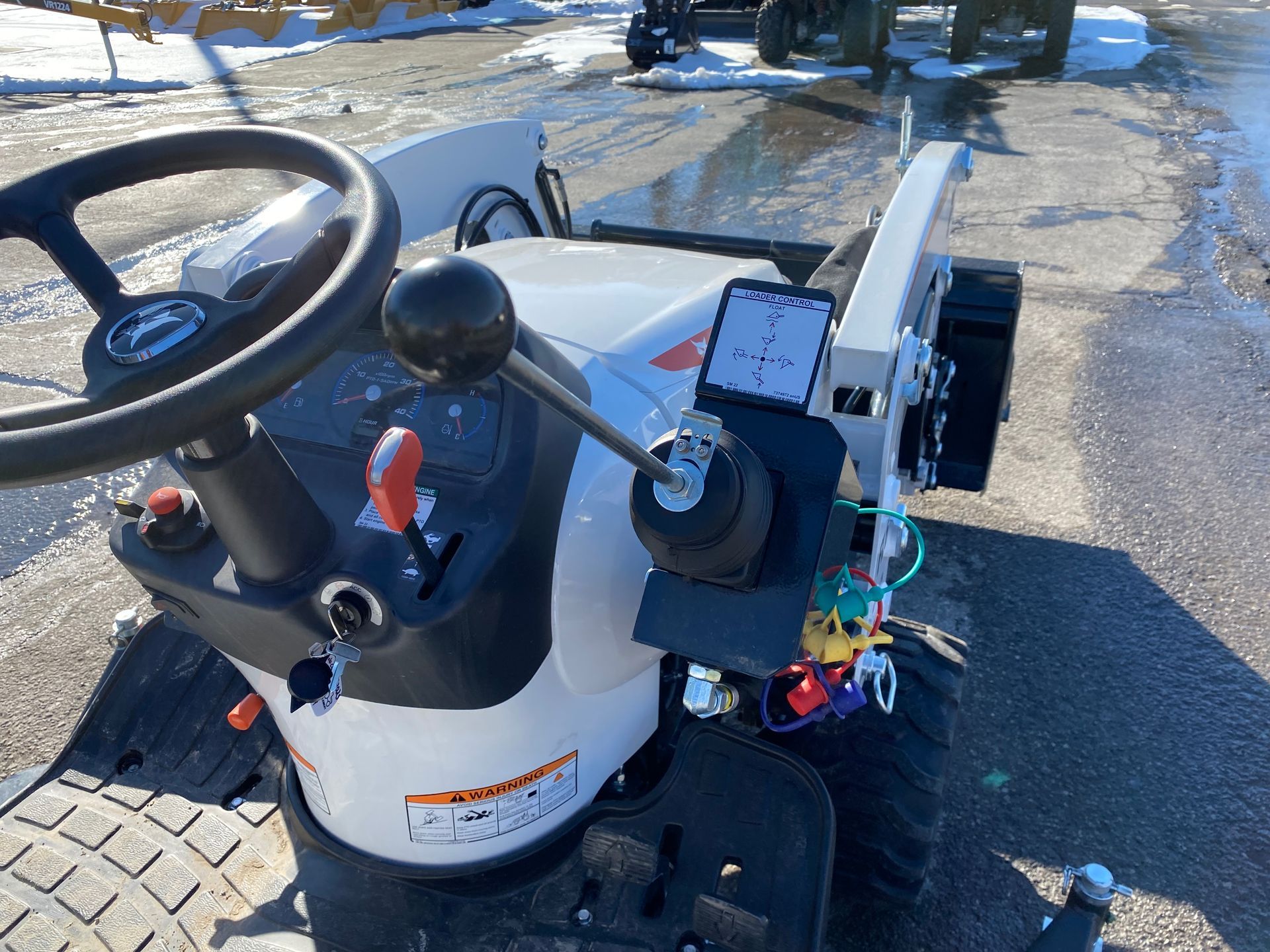 White tractor's dashboard, steering wheel, and control panel with mounted smartphone.