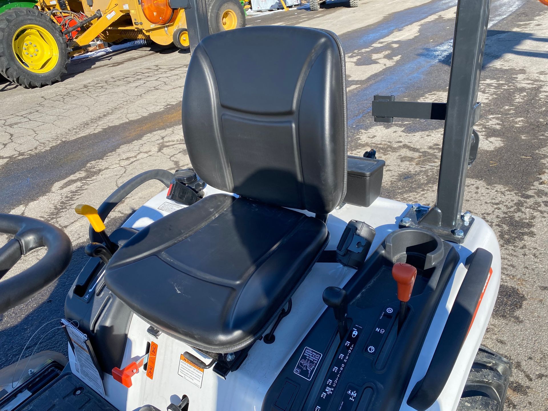 Tractor seat and controls, white body, black seat. Levers, gauges, cup holder.