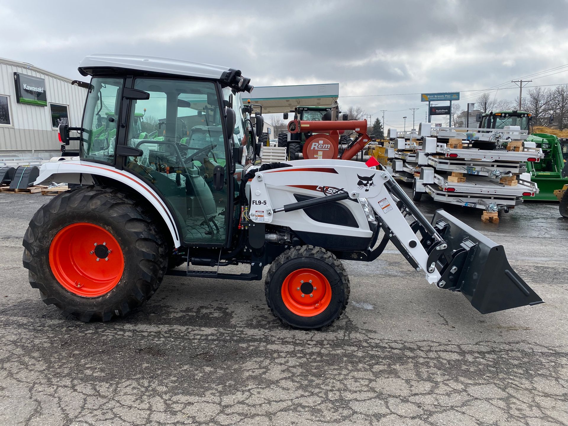White Bobcat tractor with a front loader and orange wheels, parked outdoors.