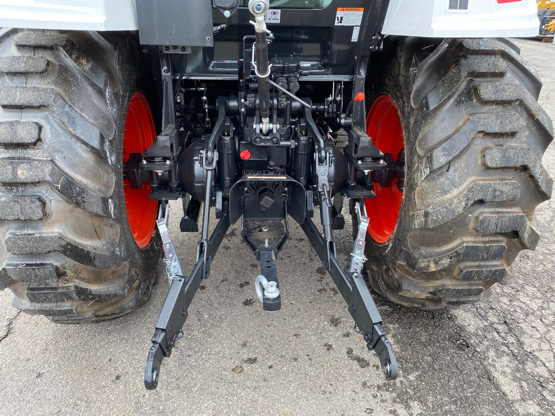 Rear view of a tractor with orange wheels, hitch, and black support arms.