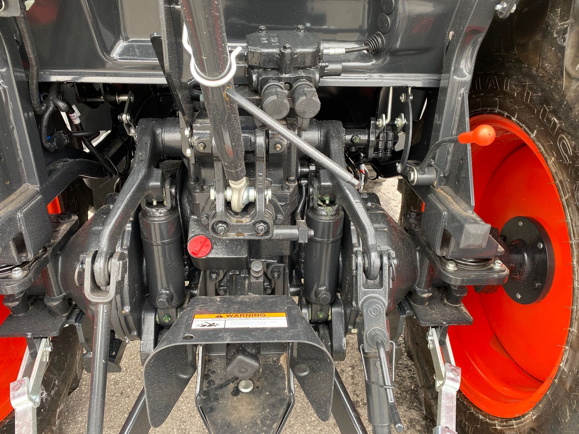 Rear view of an orange and black tractor with three-point hitch.