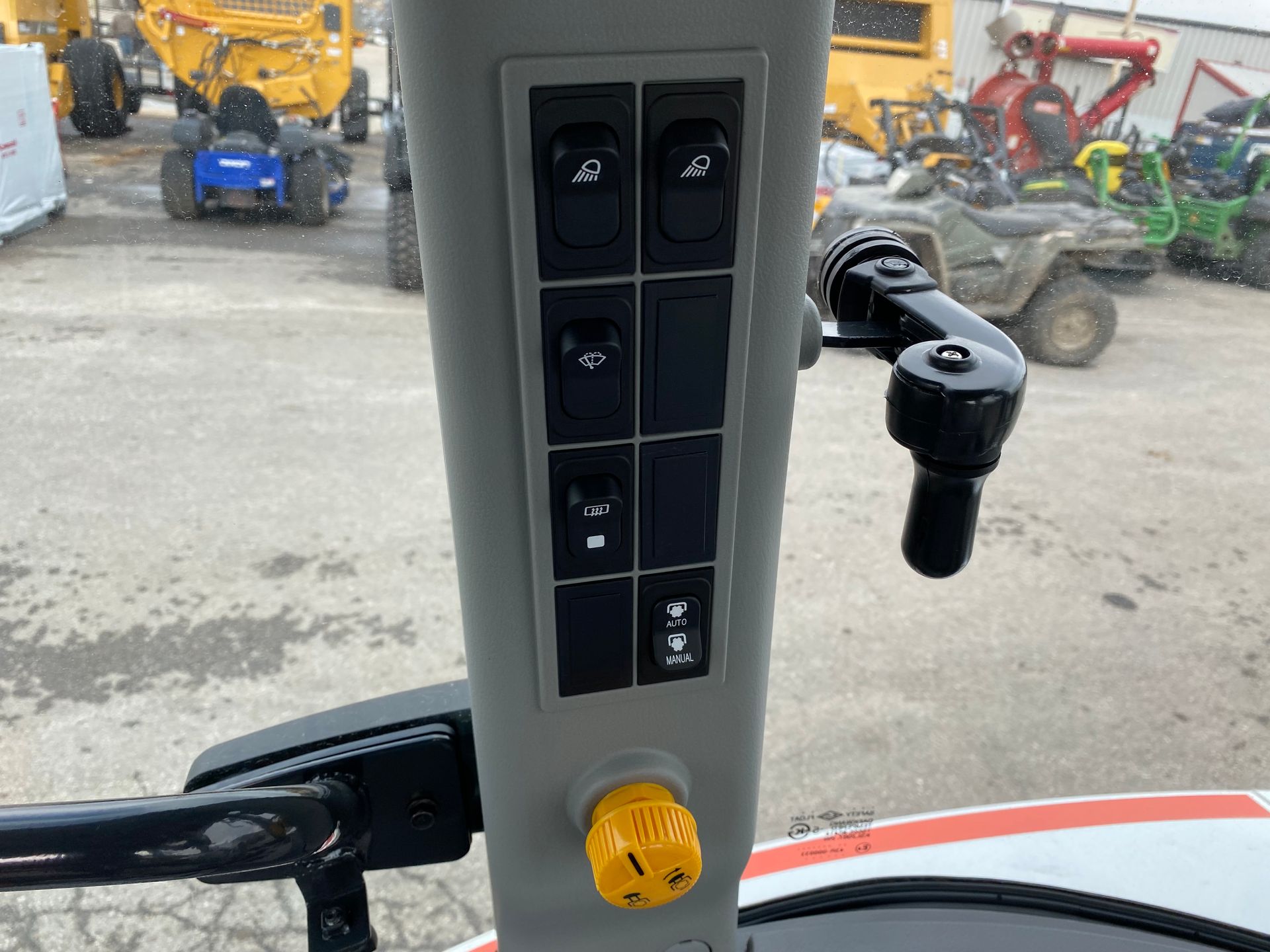 Control panel with switches and joystick in a tractor cab; outdoor setting.