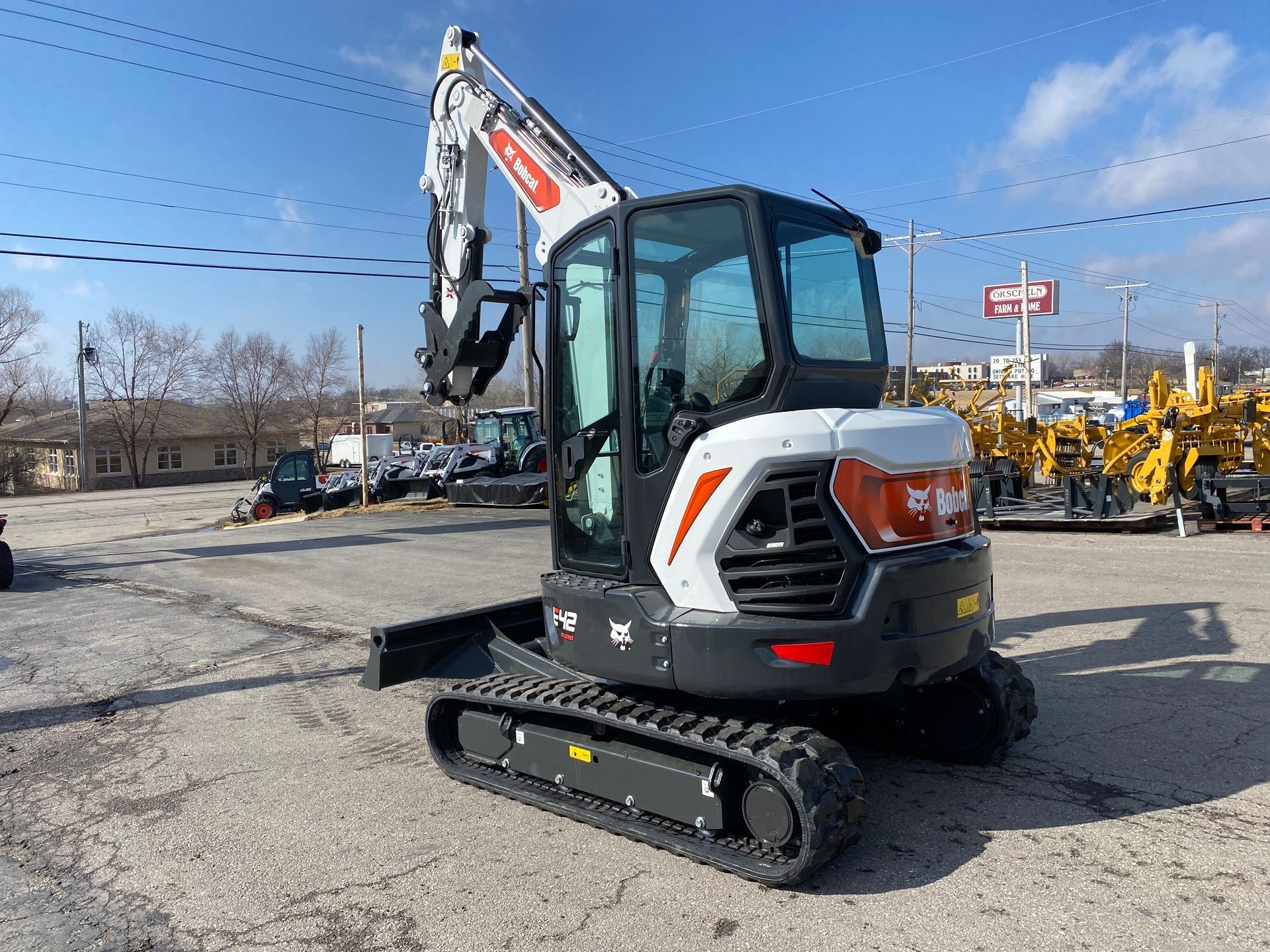 A white and black Bobcat excavator on a paved lot on a sunny day.