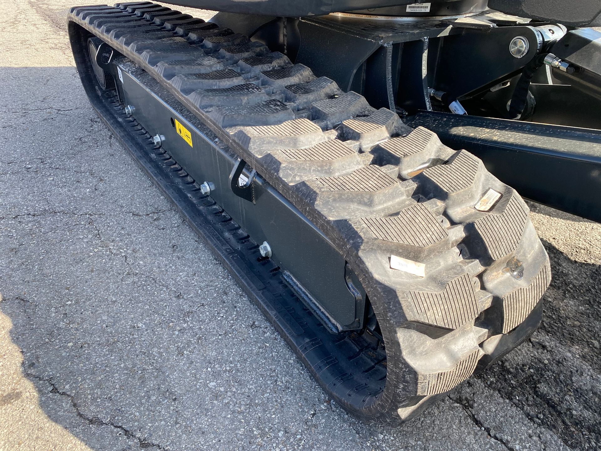 Black rubber track of a small excavator on asphalt.