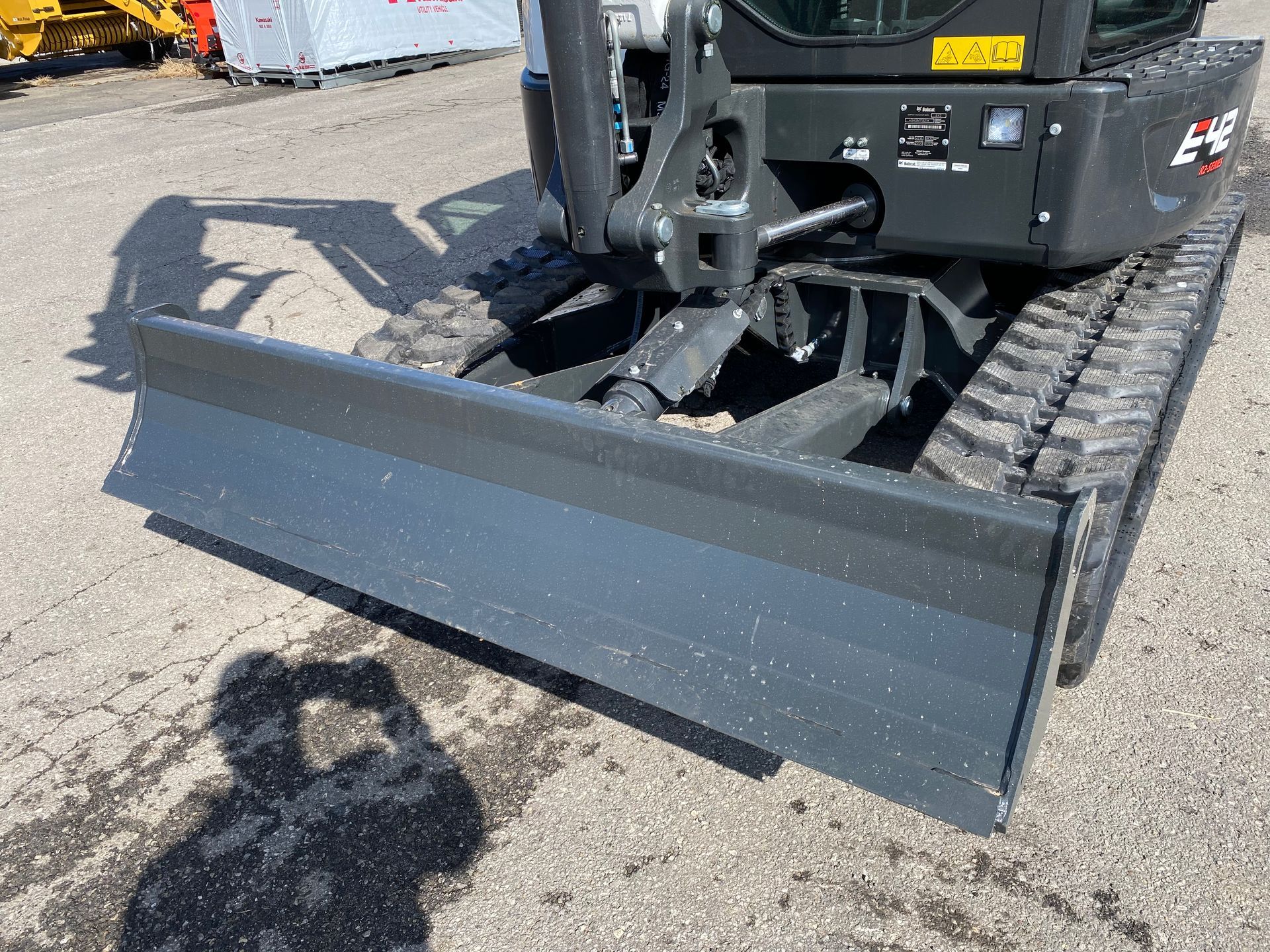 Mini excavator with a front blade on a gravel surface.