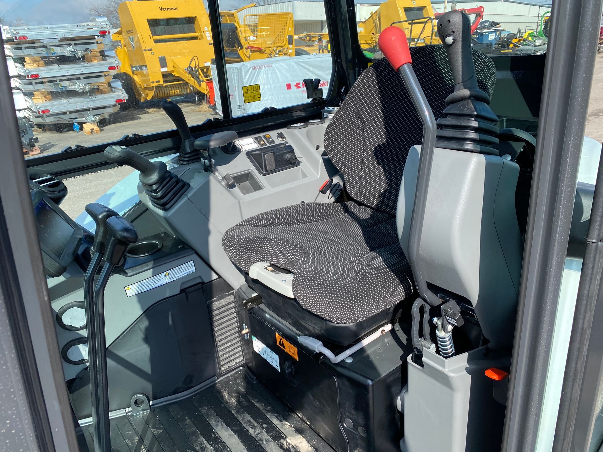 Interior of heavy machinery cab with seat, controls, and glass windows.