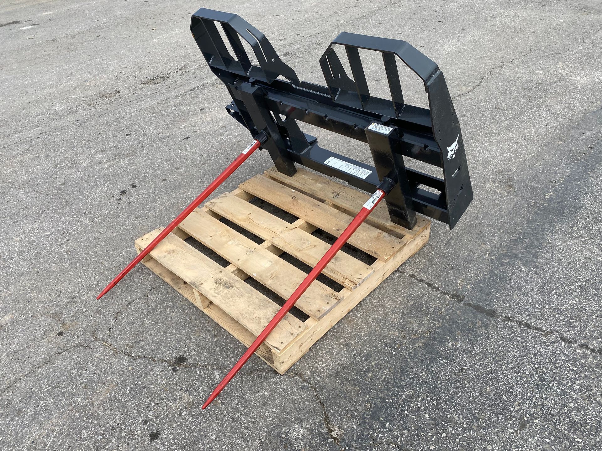 Hay spear attachment on a wooden pallet, with two red spears angled outward.
