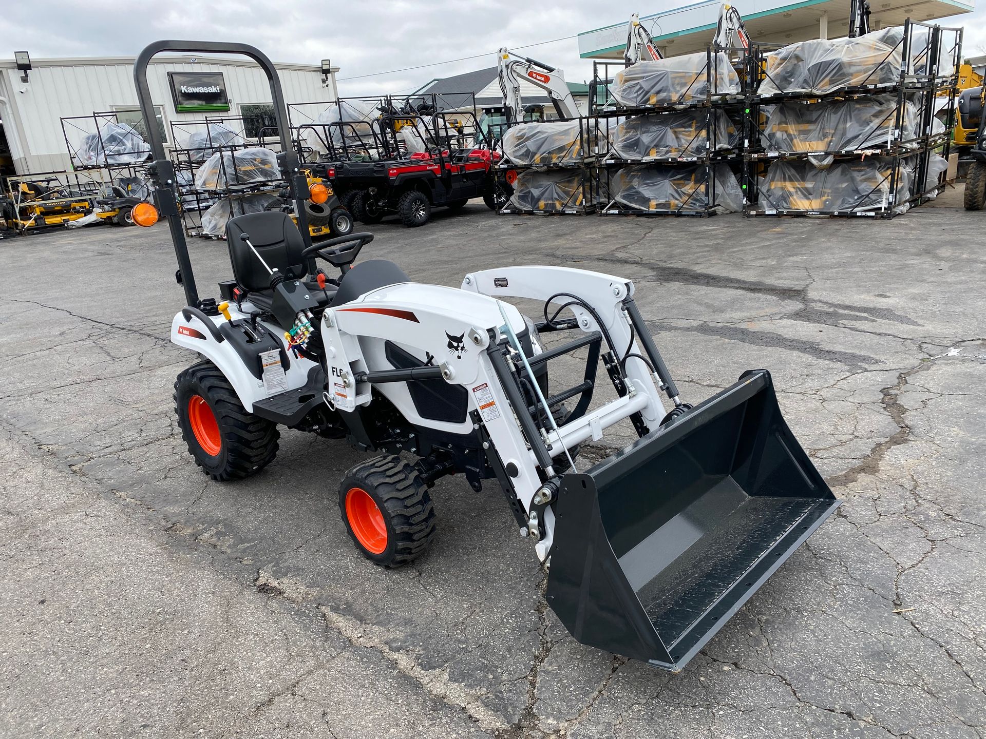 White Bobcat tractor with orange wheels and front loader on pavement.