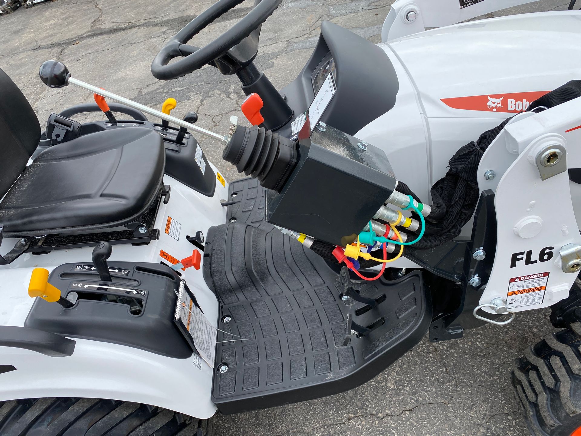 White Bobcat tractor cockpit with controls, including a joystick and levers.