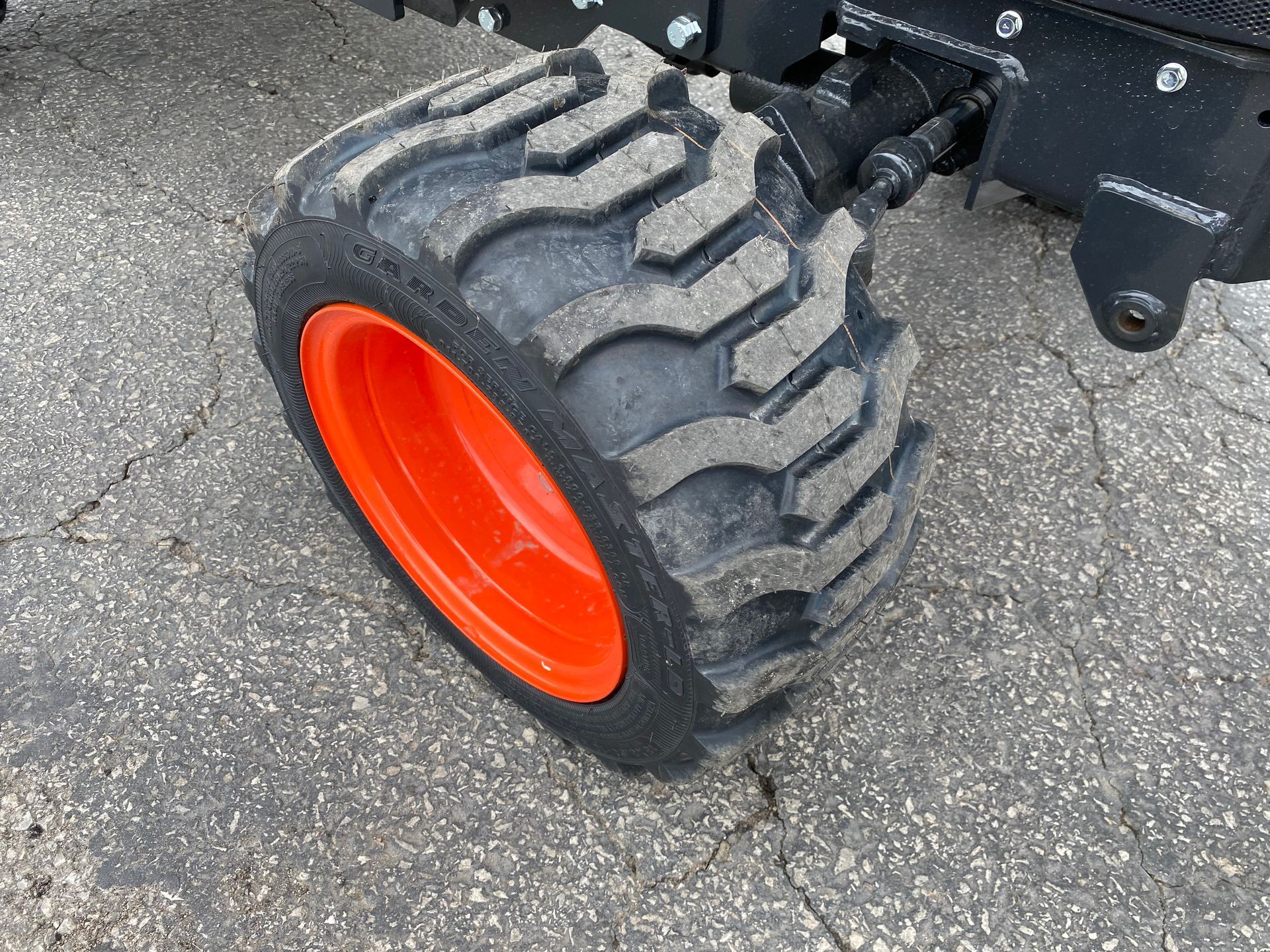 Orange wheel on a black tractor, on asphalt.