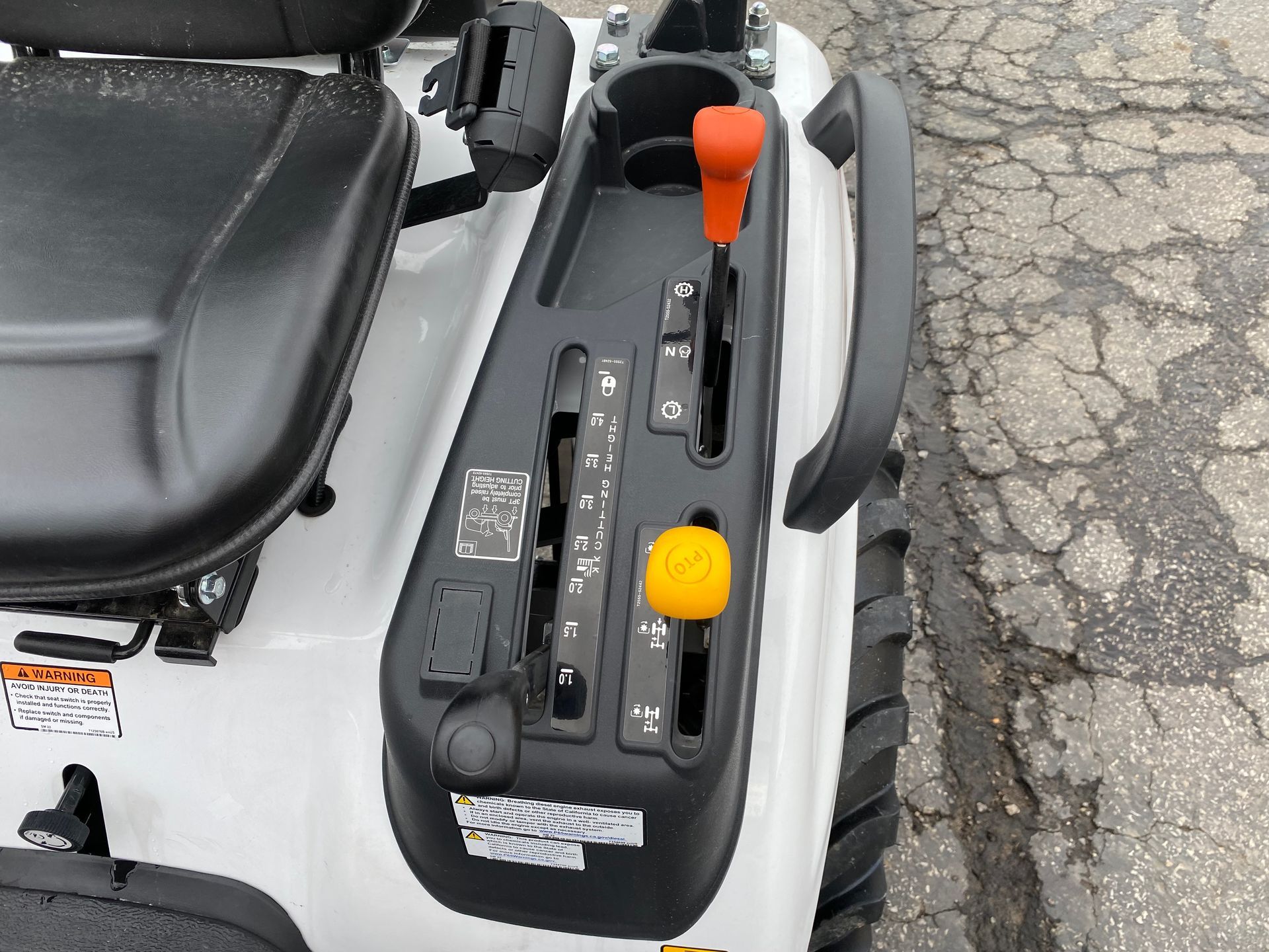 Control panel on a white mower, with orange and yellow levers, and a cup holder.