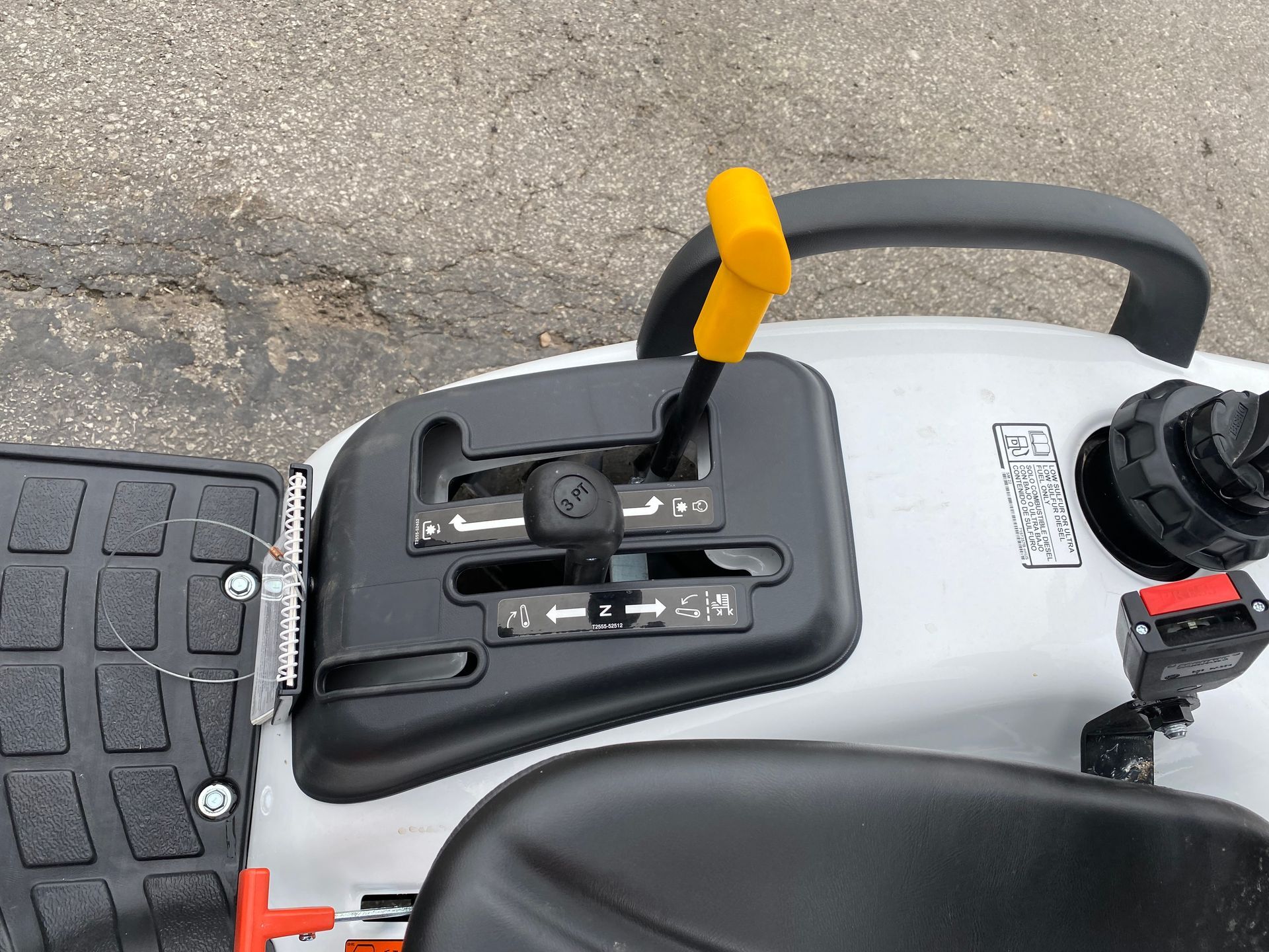 Black control panel on white tractor. Yellow lever in the middle. Forward, reverse, and speed control labels.